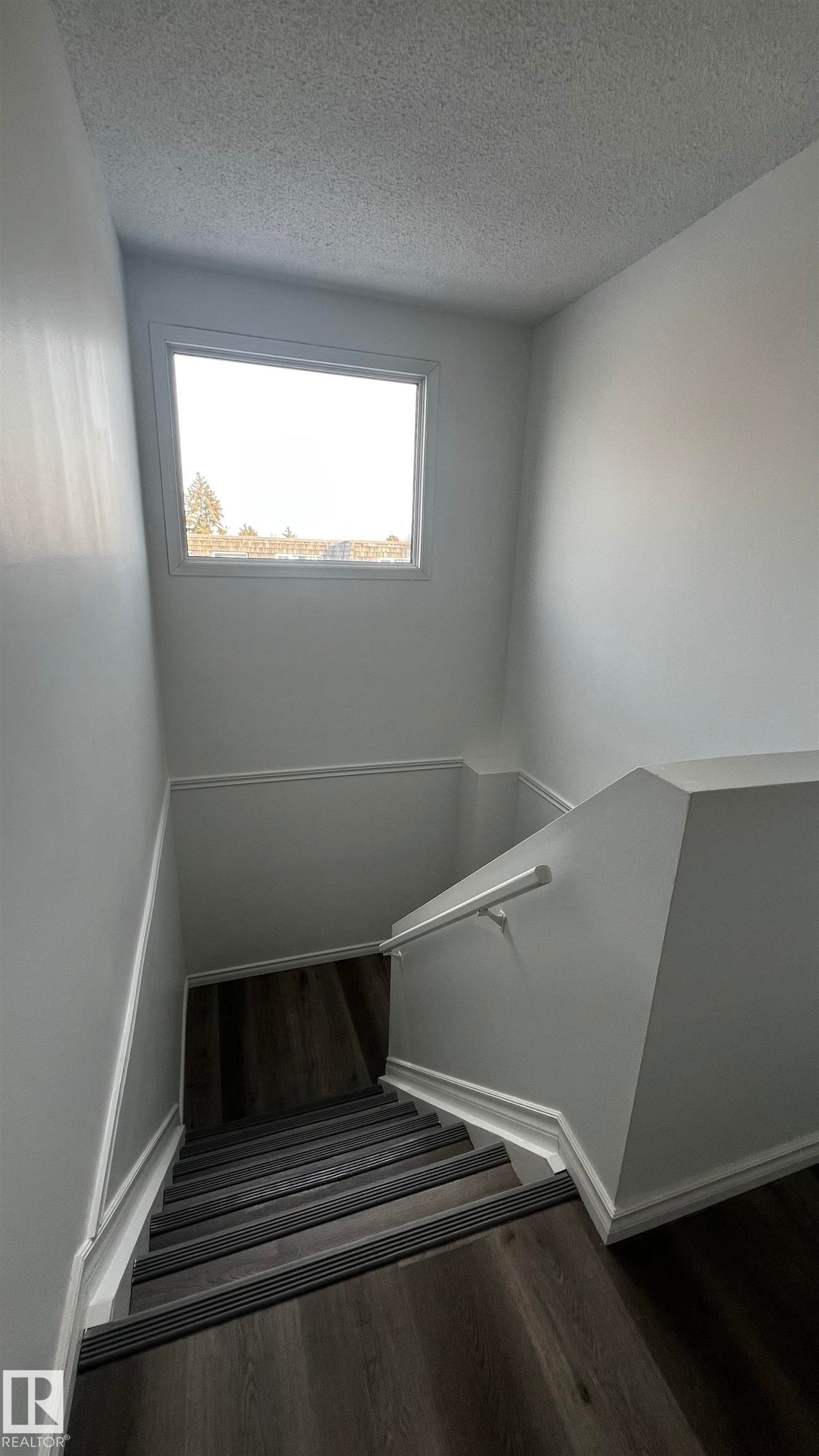 Staircase featuring dark wood-style flooring, white walls, and a window providing natural light - 3323 107 Avenue Nw, Edmonton, AB - Indoor Photo Showing Other Room