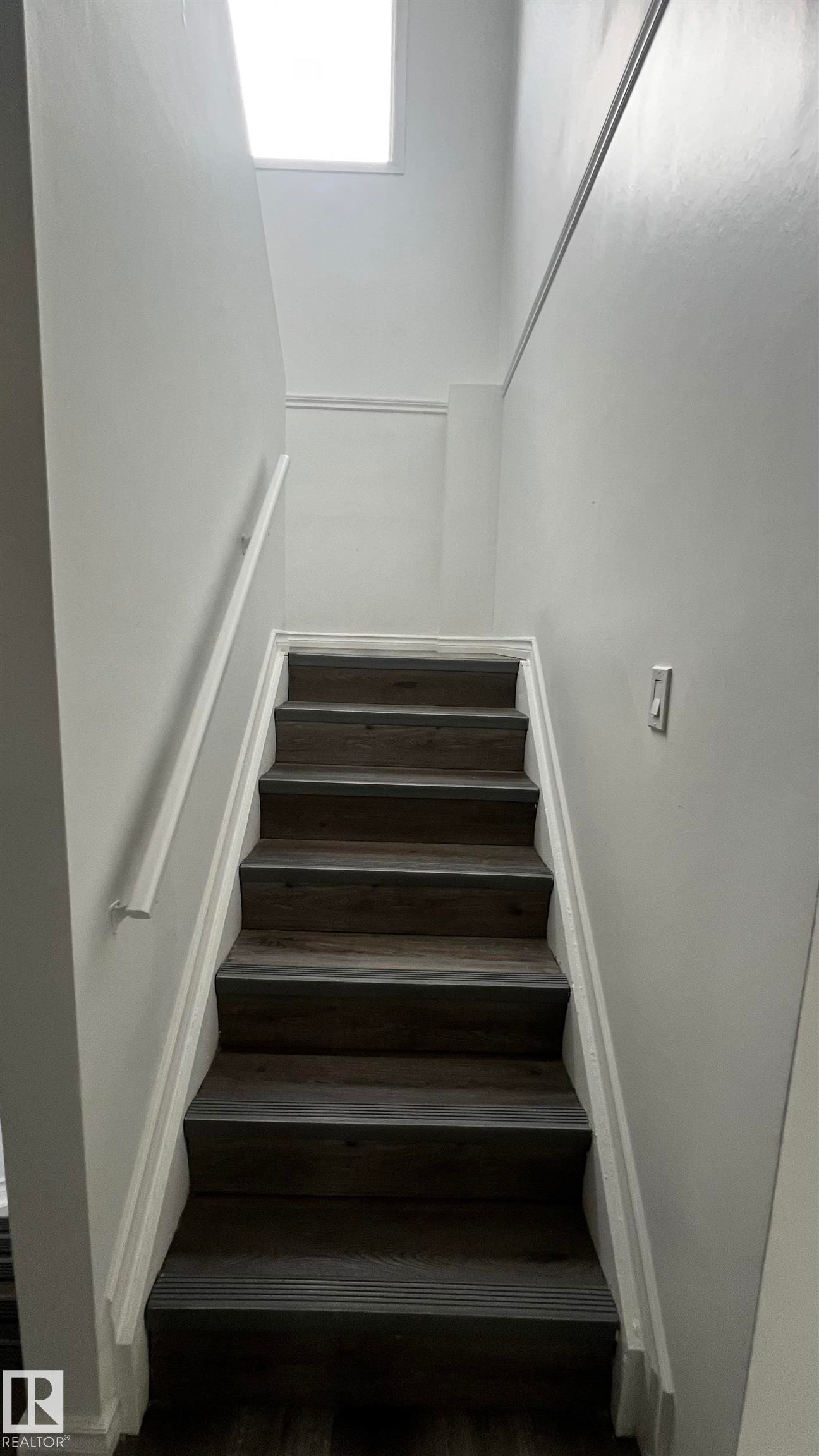Staircase featuring dark wood-look treads, white risers, and a white handrail - 3323 107 Avenue Nw, Edmonton, AB - Indoor Photo Showing Other Room