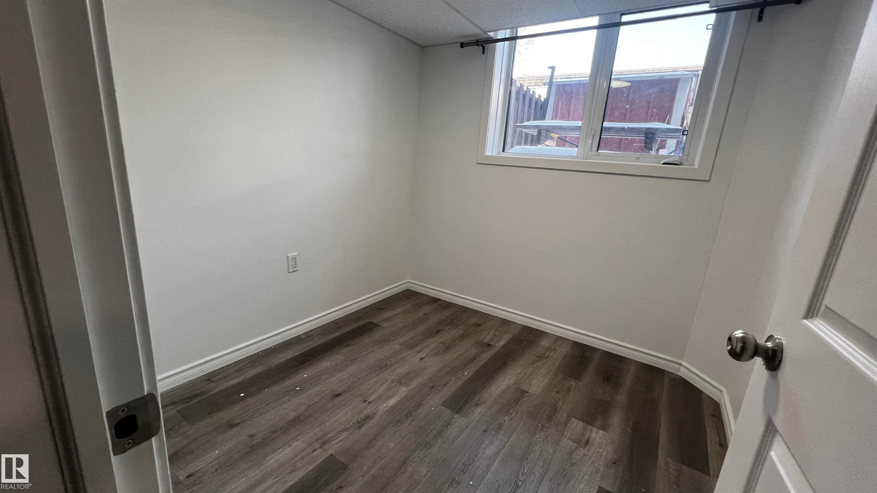 This room features wood-look flooring, white walls, and a window providing natural light - 3323 107 Avenue Nw, Edmonton, AB - Indoor Photo Showing Other Room