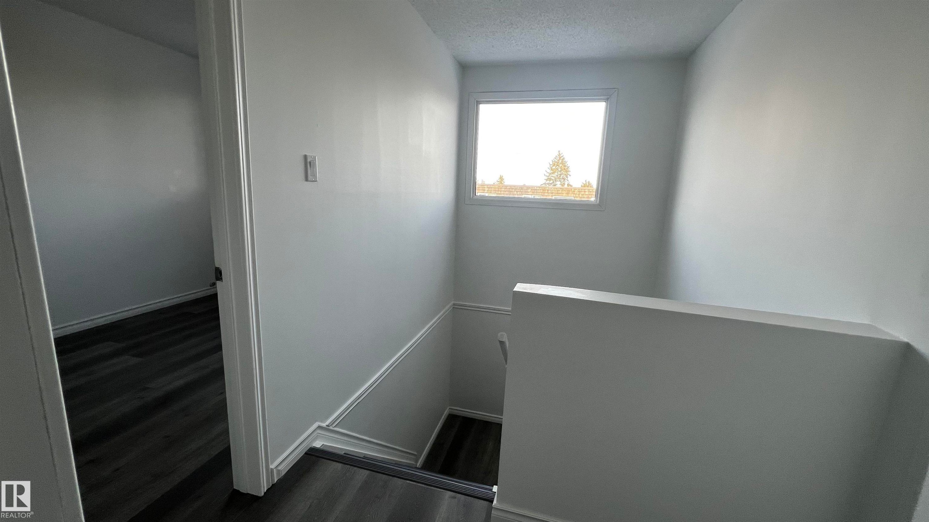 Stairwell featuring white walls, a window providing natural light, and dark wood-style flooring - 3323 107 Avenue Nw, Edmonton, AB - Indoor Photo Showing Other Room