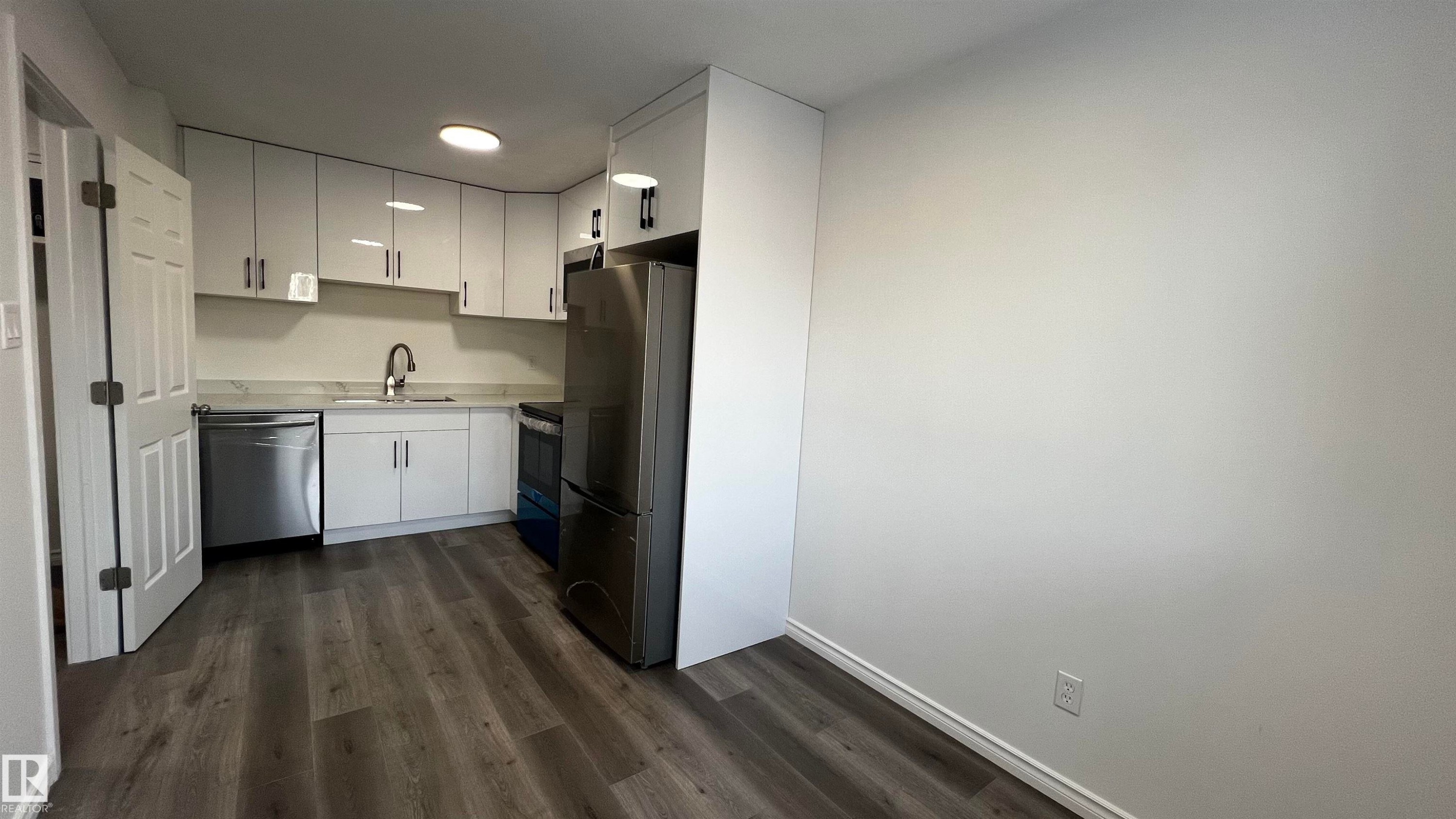 Kitchen featuring light-colored cabinetry, stainless steel appliances, and wood-look flooring - 3323 107 Avenue Nw, Edmonton, AB - Indoor Photo Showing Kitchen