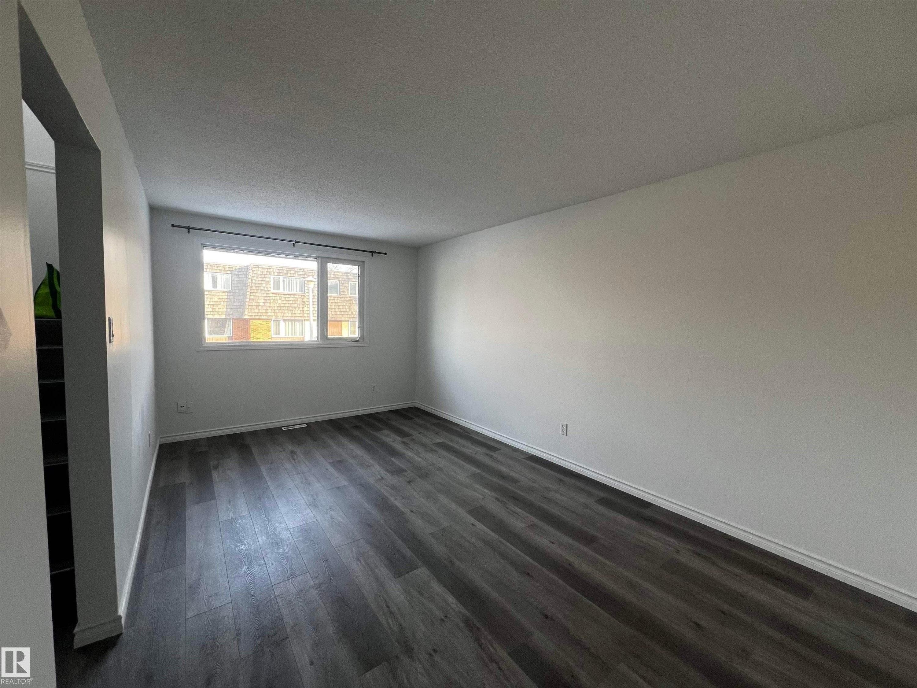This living space features dark wood-style flooring and a window providing natural light - 3323 107 Avenue Nw, Edmonton, AB - Indoor Photo Showing Other Room