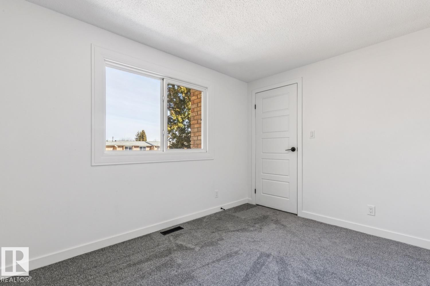 This bright room features a window providing natural light, a white paneled door, and gray carpeting - 95 Ridgewood Terrace, St. Albert, AB - Indoor Photo Showing Other Room