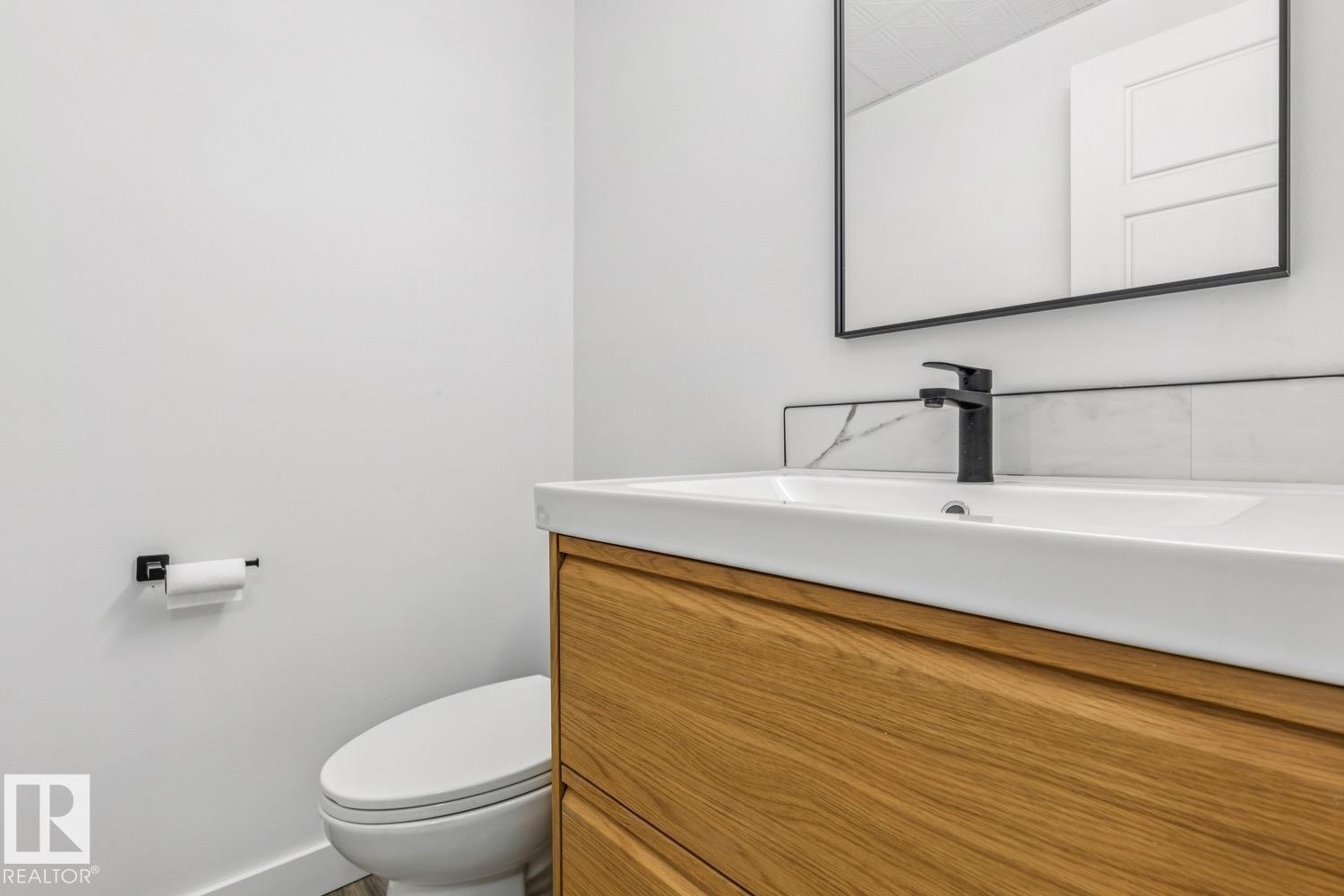 Bathroom featuring a white vanity with a wooden base, a black faucet, and a black-framed mirror - 95 Ridgewood Terrace, St. Albert, AB - Indoor Photo Showing Bathroom