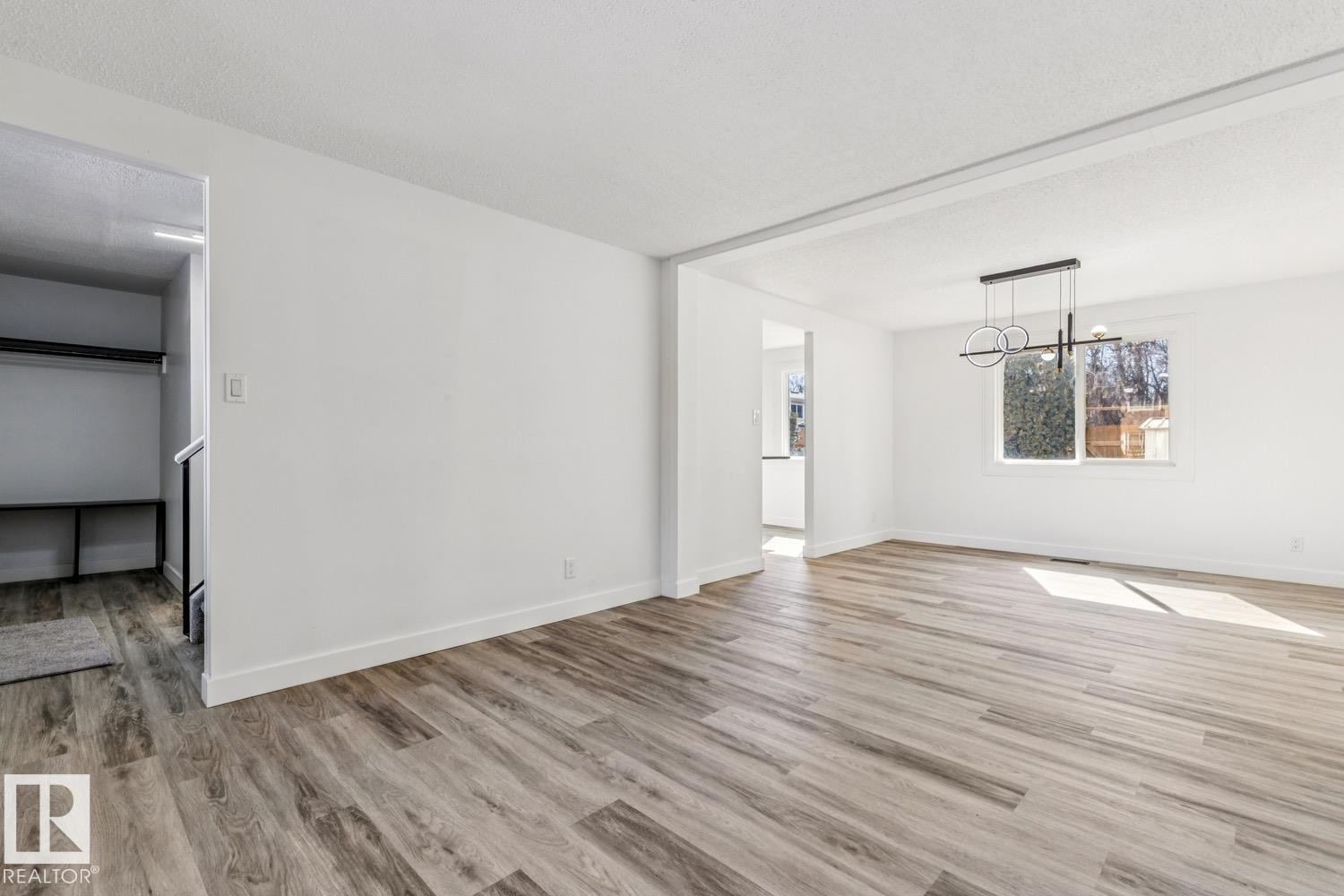 This bright room features wide plank flooring, a modern chandelier, and a large window providing natural light - 95 Ridgewood Terrace, St. Albert, AB - Indoor