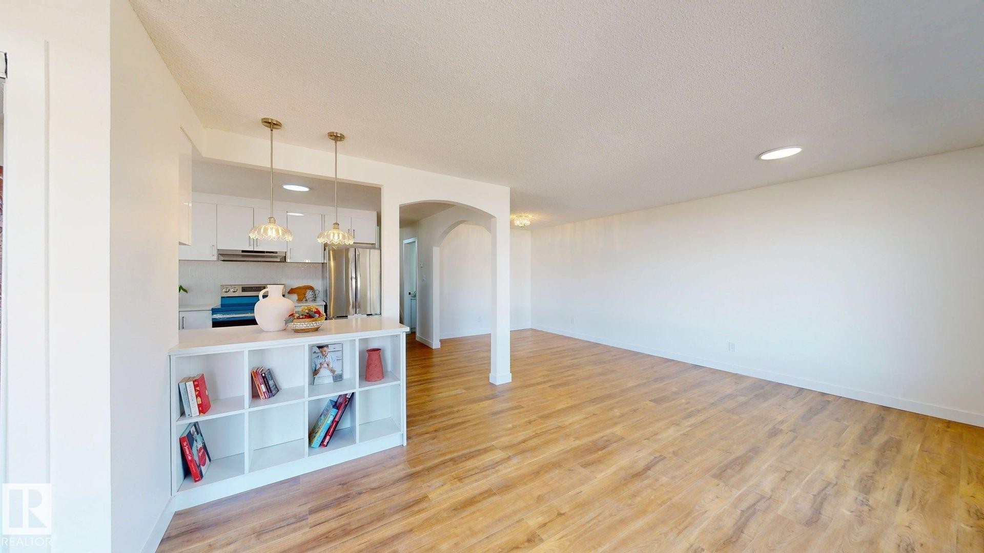 The open-concept living area features wood-look flooring and recessed lighting - 8515 86 Avenue, Edmonton, AB - Indoor Photo Showing Other Room