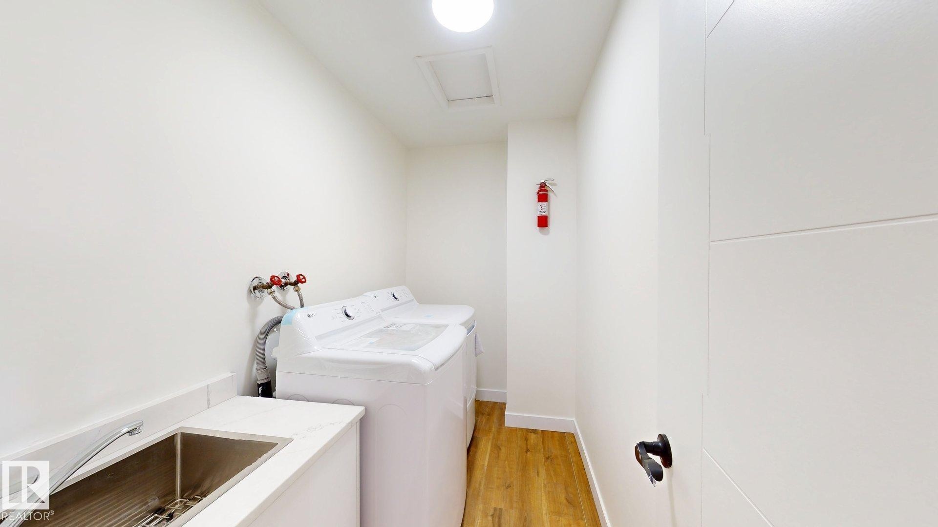 This utility space features a stainless steel sink, a countertop, and wood flooring - 8515 86 Avenue, Edmonton, AB - Indoor Photo Showing Laundry Room