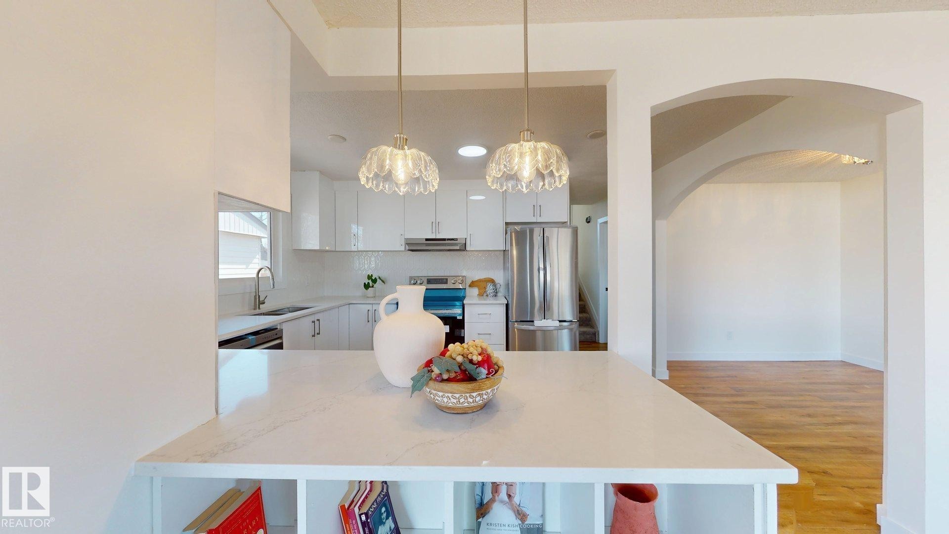 Kitchen featuring white cabinetry, stainless steel appliances, and a central island with integrated shelving - 8515 86 Avenue, Edmonton, AB - Indoor