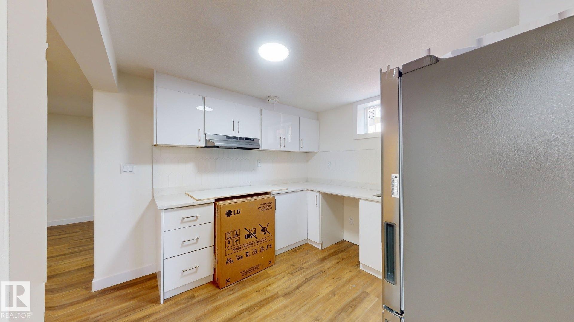 Kitchen featuring white cabinetry, light countertops, and wood-look flooring - 8515 86 Avenue, Edmonton, AB - Indoor