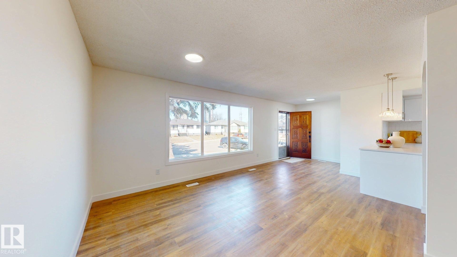 Spacious living area featuring light wood flooring, recessed lighting, and a large window providing ample natural light - 8515 86 Avenue, Edmonton, AB - Indoor