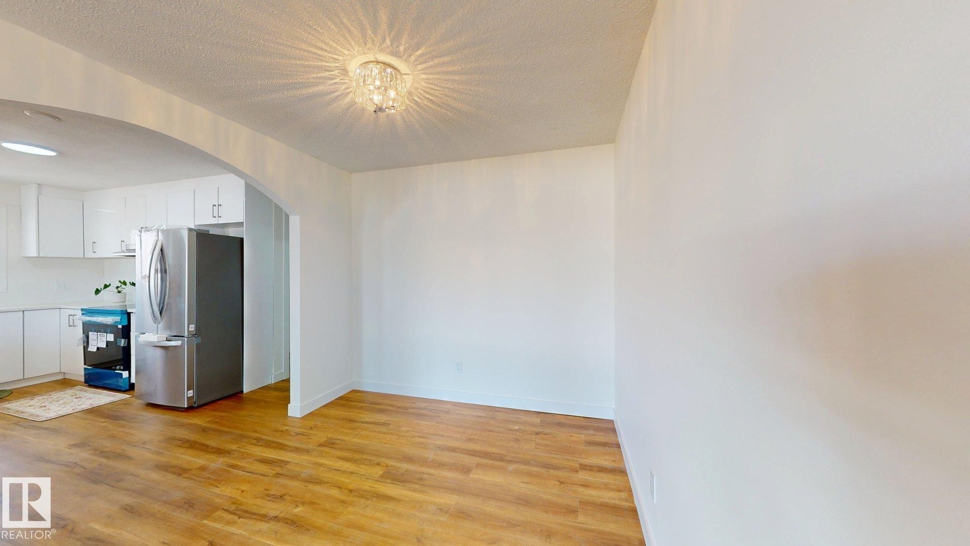 The property features an open living space with wood flooring, an arched doorway, and a decorative ceiling light fixture - 8515 86 Avenue, Edmonton, AB - Indoor Photo Showing Kitchen