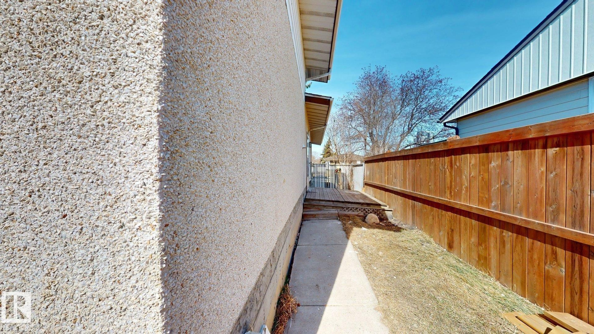 The property features exterior stucco siding and a wooden fence along the side yard - 8515 86 Avenue, Edmonton, AB - Outdoor