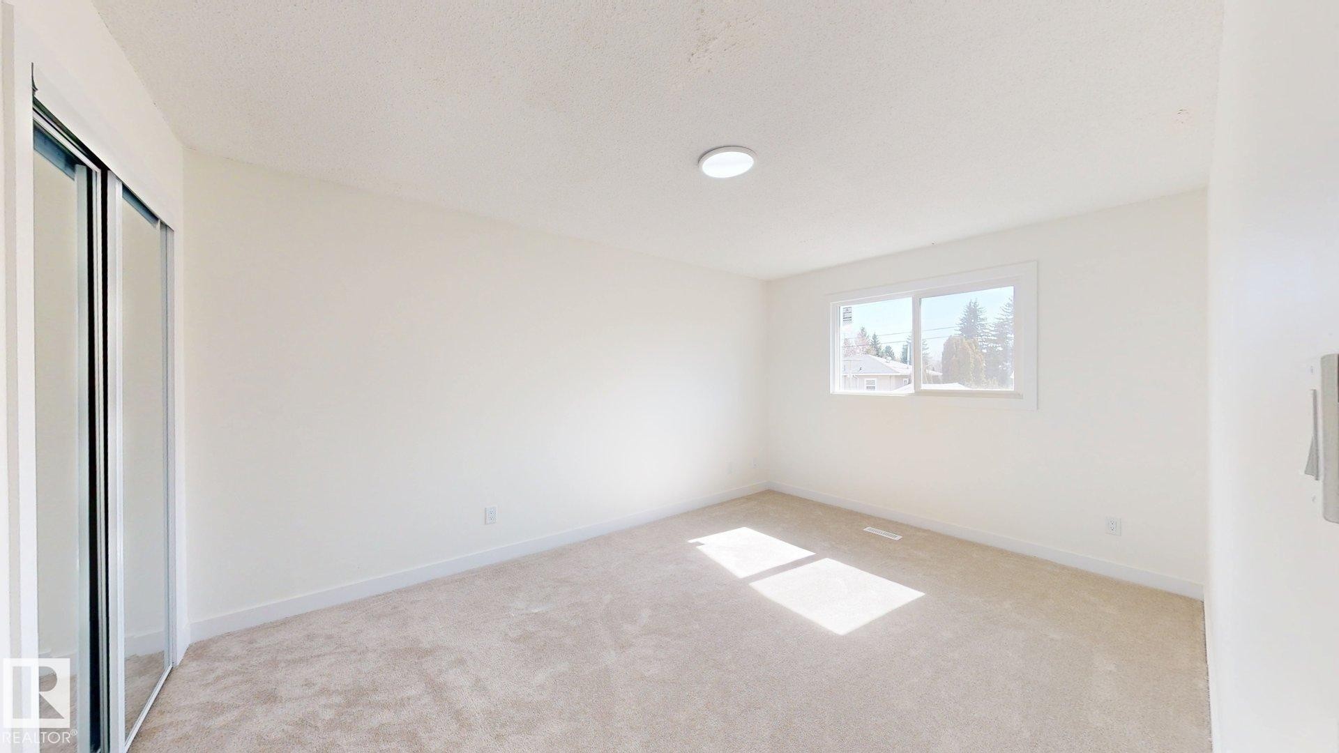 This room features light-colored carpeting, a window providing natural light, and a light fixture on the ceiling - 8515 86 Avenue, Edmonton, AB - Indoor Photo Showing Other Room