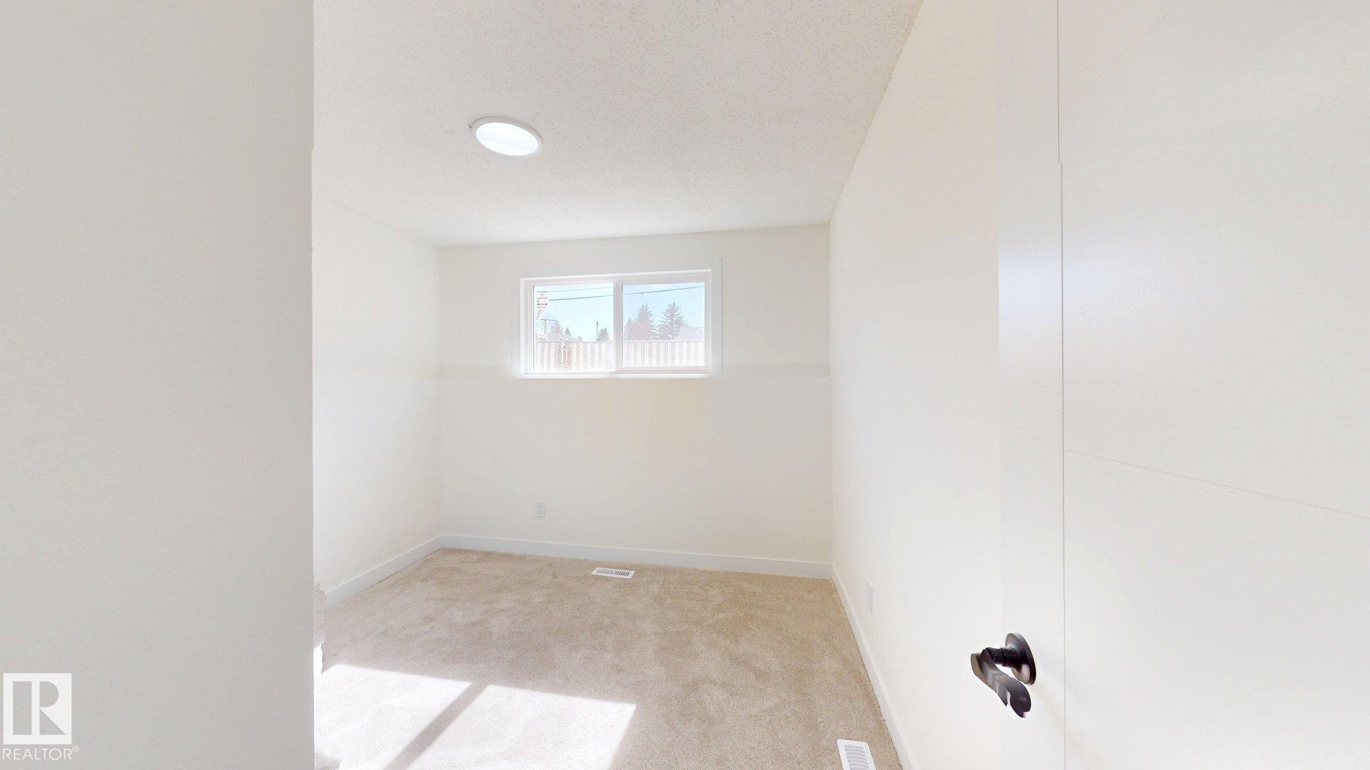 This room features a window providing natural light, a neutral carpet, and a ceiling light fixture - 8515 86 Avenue, Edmonton, AB - Indoor Photo Showing Other Room