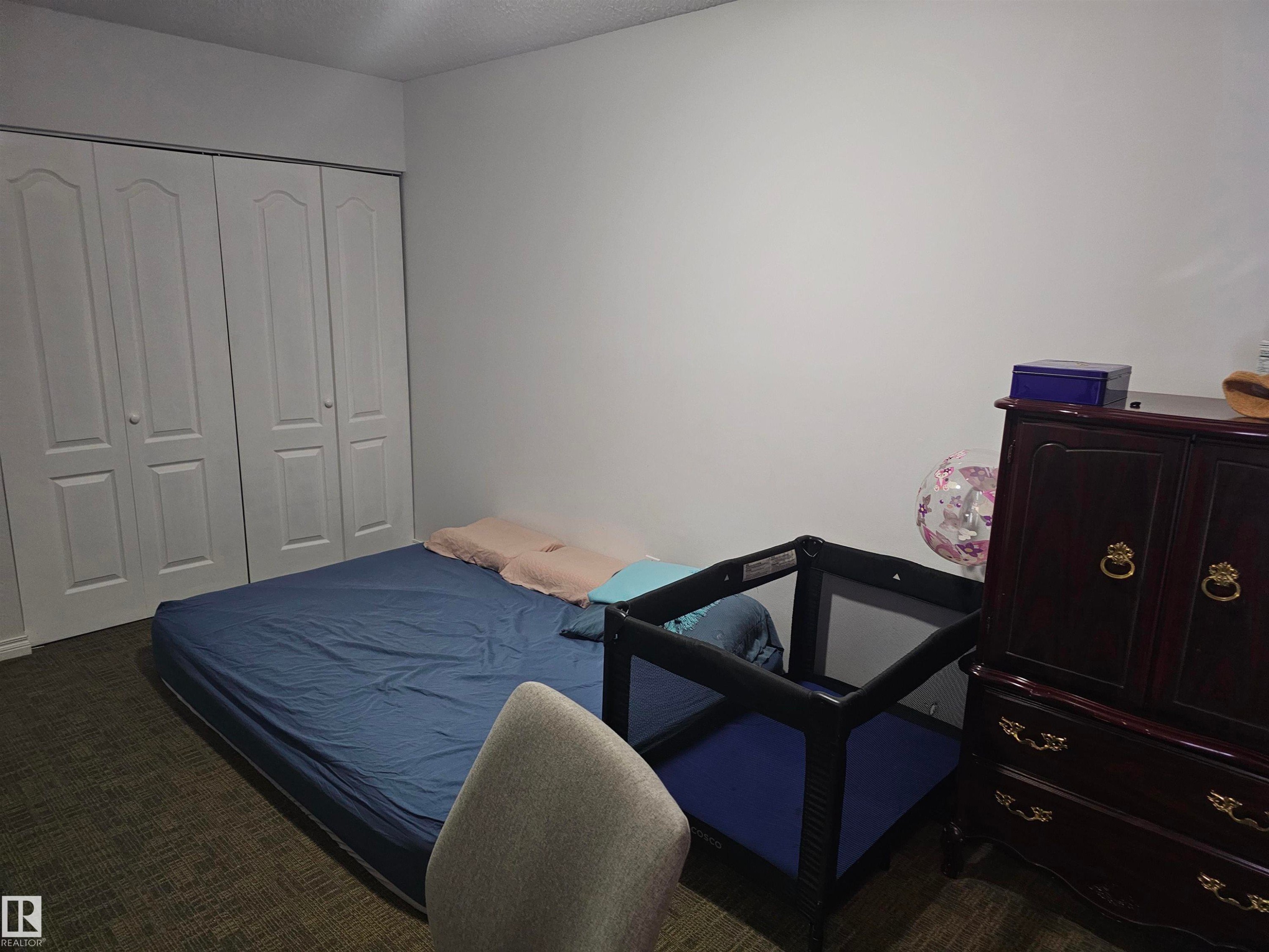 The room features a neutral color palette with white walls and dark patterned carpeting - 844 Erin Place, Edmonton, AB - Indoor Photo Showing Bedroom