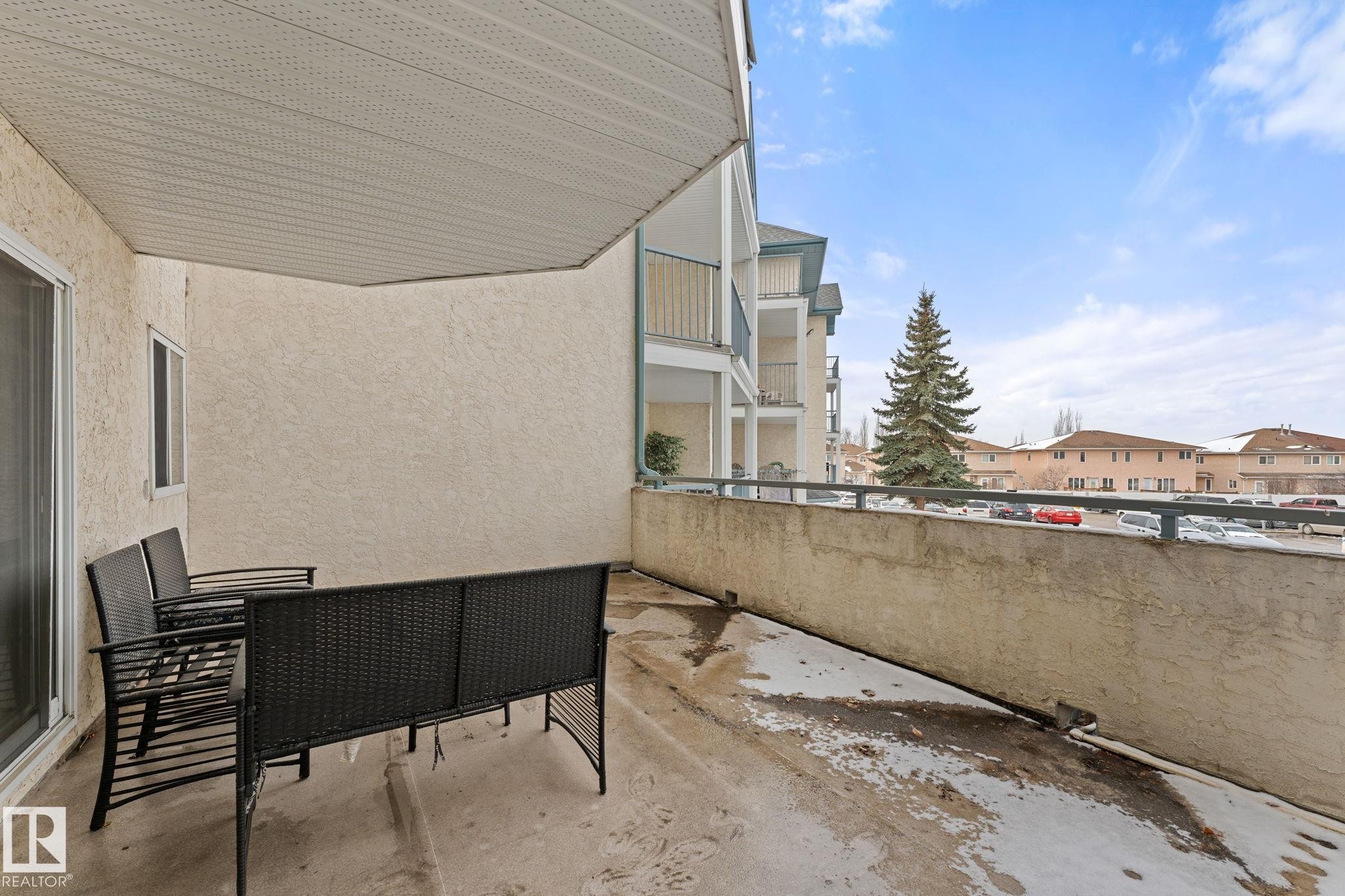 The property features a private balcony with a concrete floor and a solid wall on one side - 208 6710 158 Avenue, Edmonton, AB