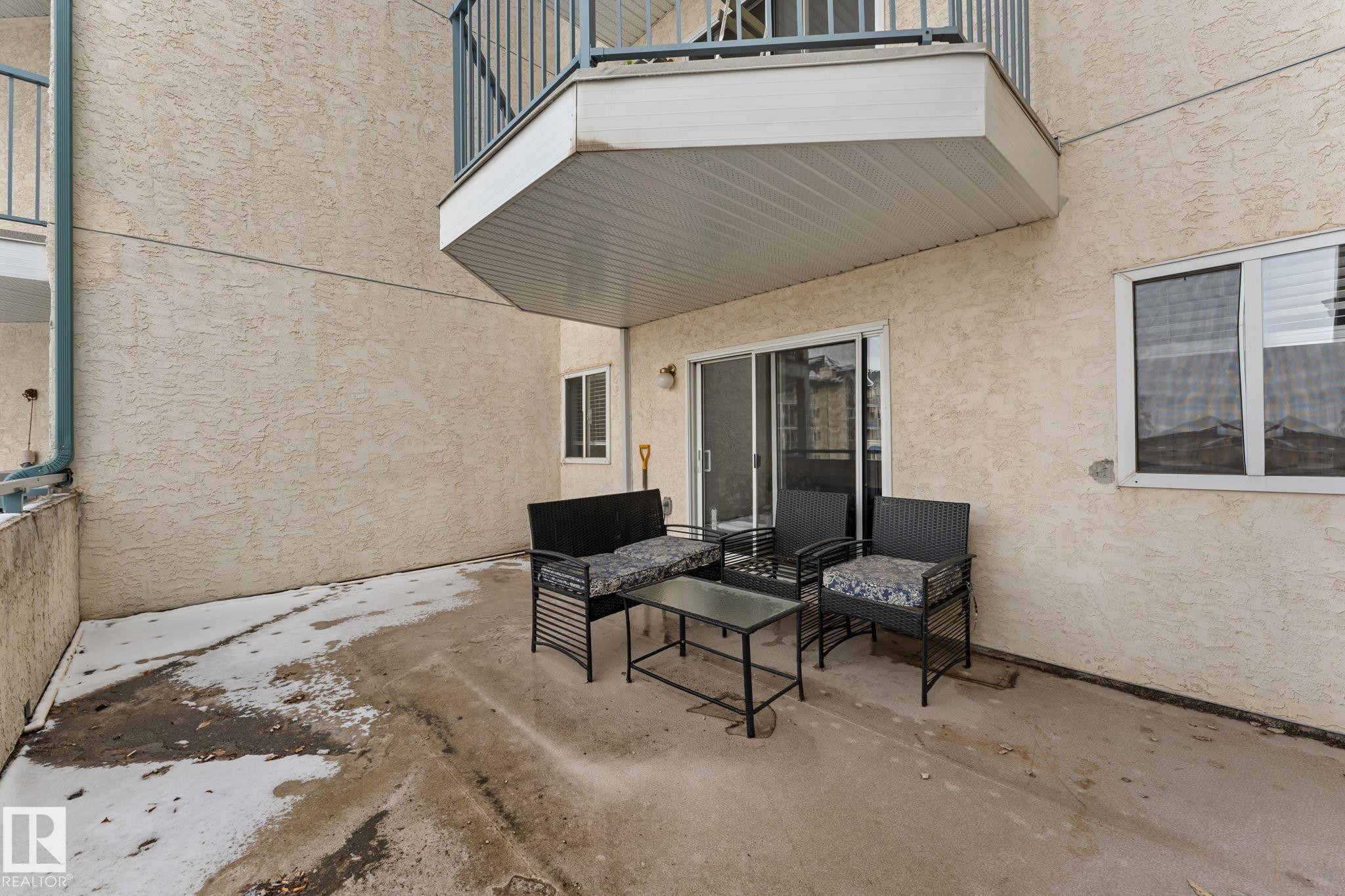 The property features a concrete patio area with direct access via sliding glass doors - 208 6710 158 Avenue, Edmonton, AB