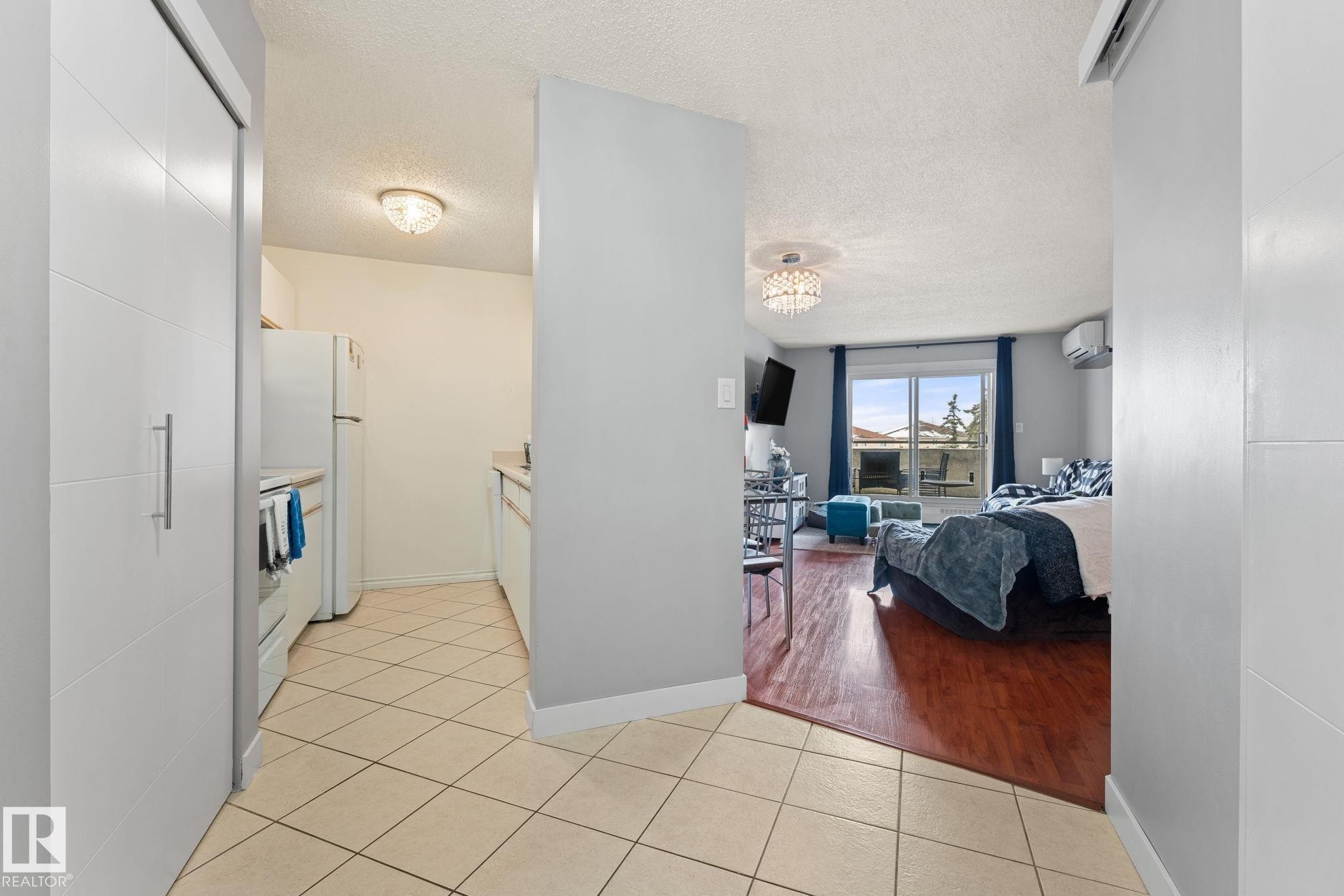 The property features a kitchen with tiled floors and white appliances - 208 6710 158 Avenue, Edmonton, AB