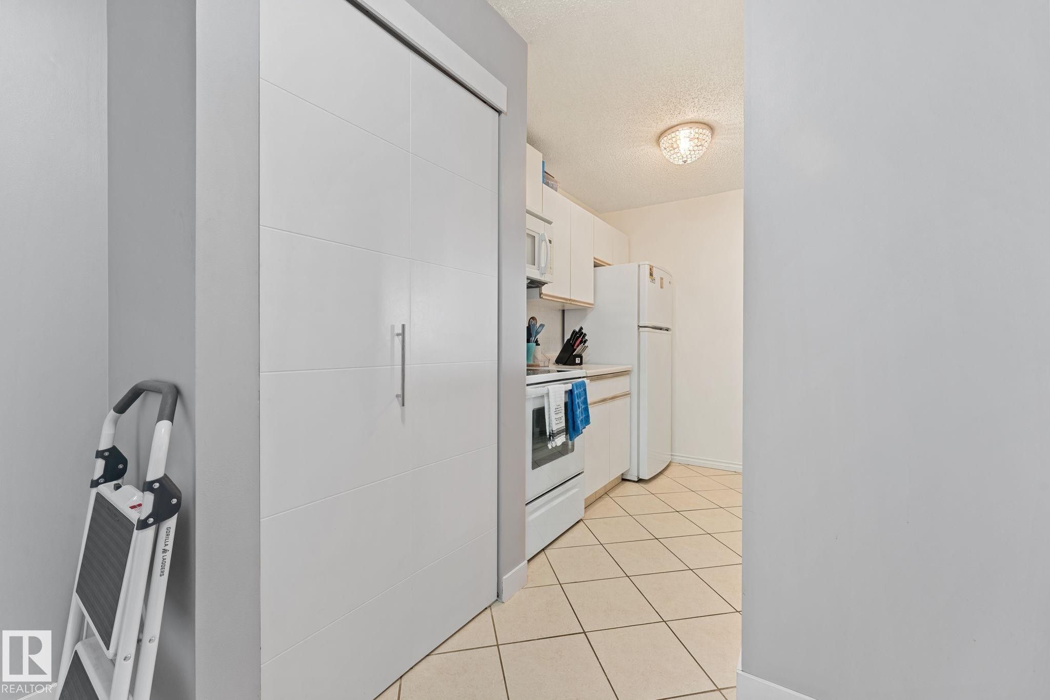 The kitchen features white cabinetry, a white refrigerator, and a white oven - 208 6710 158 Avenue, Edmonton, AB