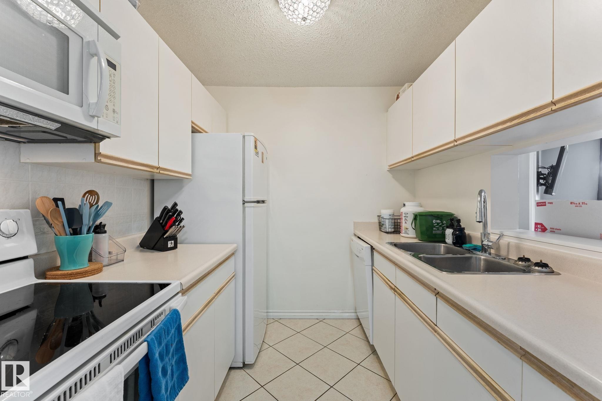 Efficient kitchen featuring white cabinetry, a double basin sink, and white appliances - 208 6710 158 Avenue, Edmonton, AB