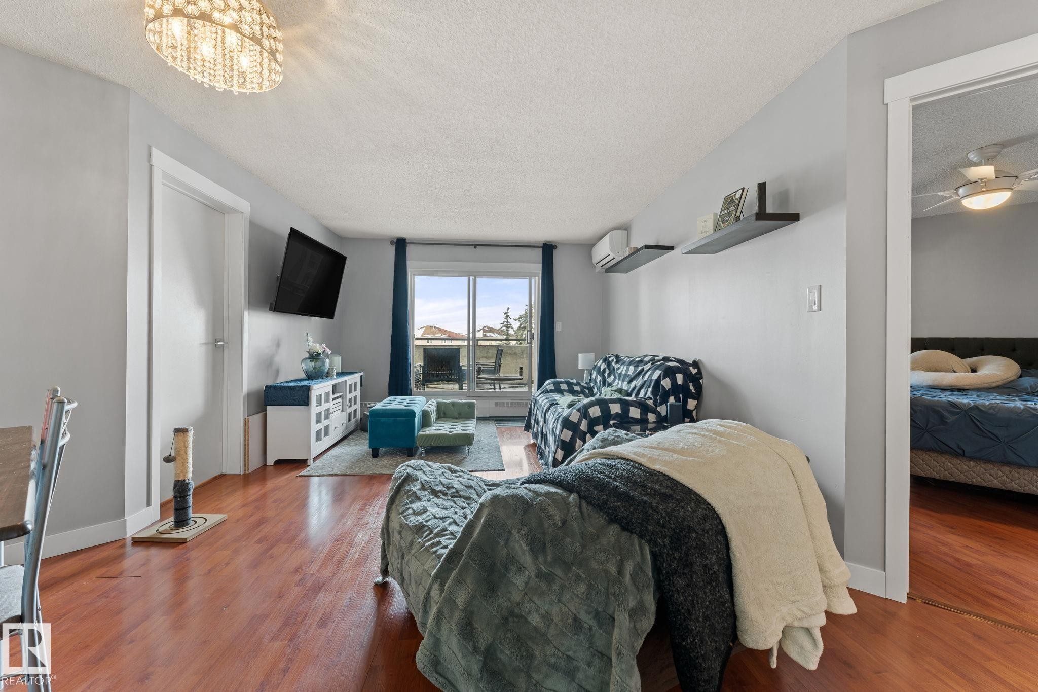 Living area featuring hardwood flooring, a decorative chandelier, and access to an outdoor balcony - 208 6710 158 Avenue, Edmonton, AB