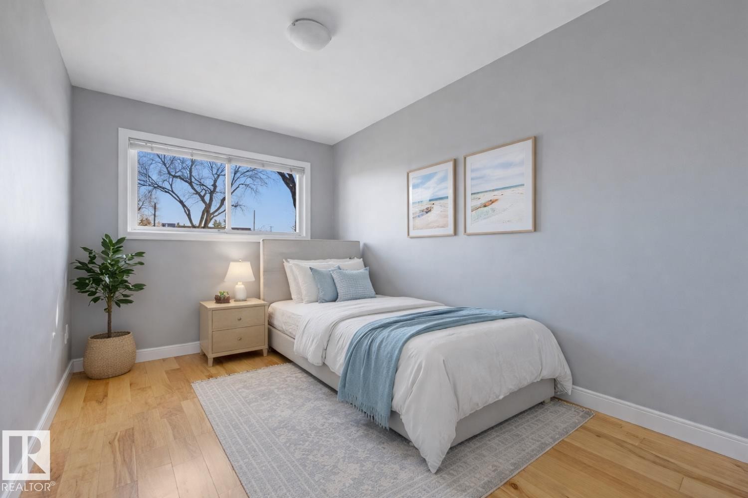 Bedroom featuring light wood floors, a window with a view of trees, and light gray walls - 10612 79 Street, Edmonton, AB