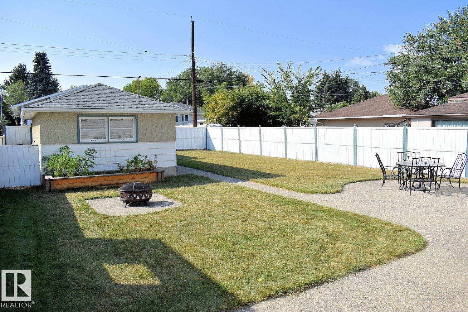 Expansive backyard with a separate garage structure, concrete patio, and a manicured lawn - 10612 79 Street, Edmonton, AB