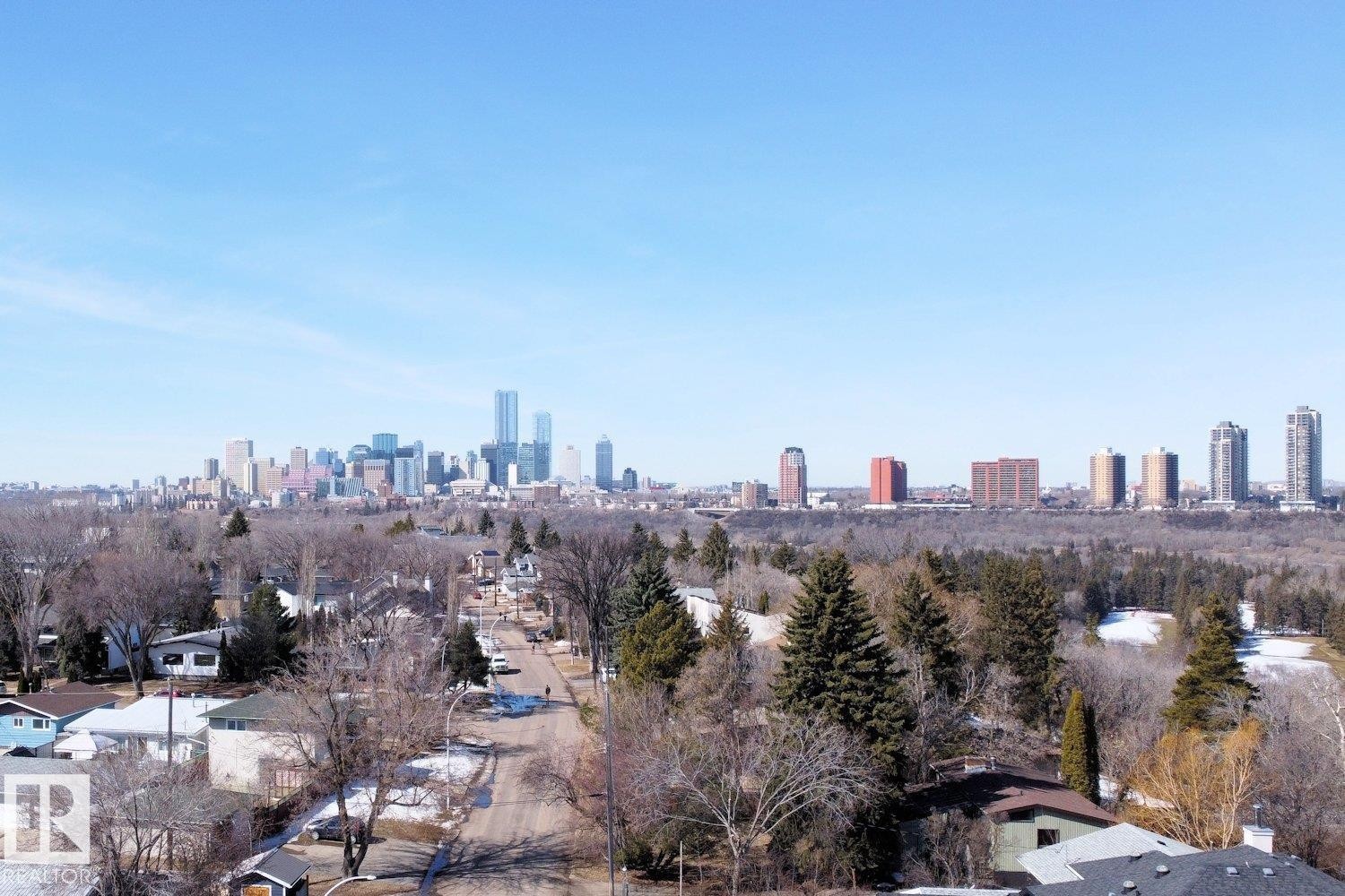 Expansive aerial perspective showcasing a cityscape backdrop with residential areas and forested terrain in the foreground - 10612 79 Street, Edmonton, AB