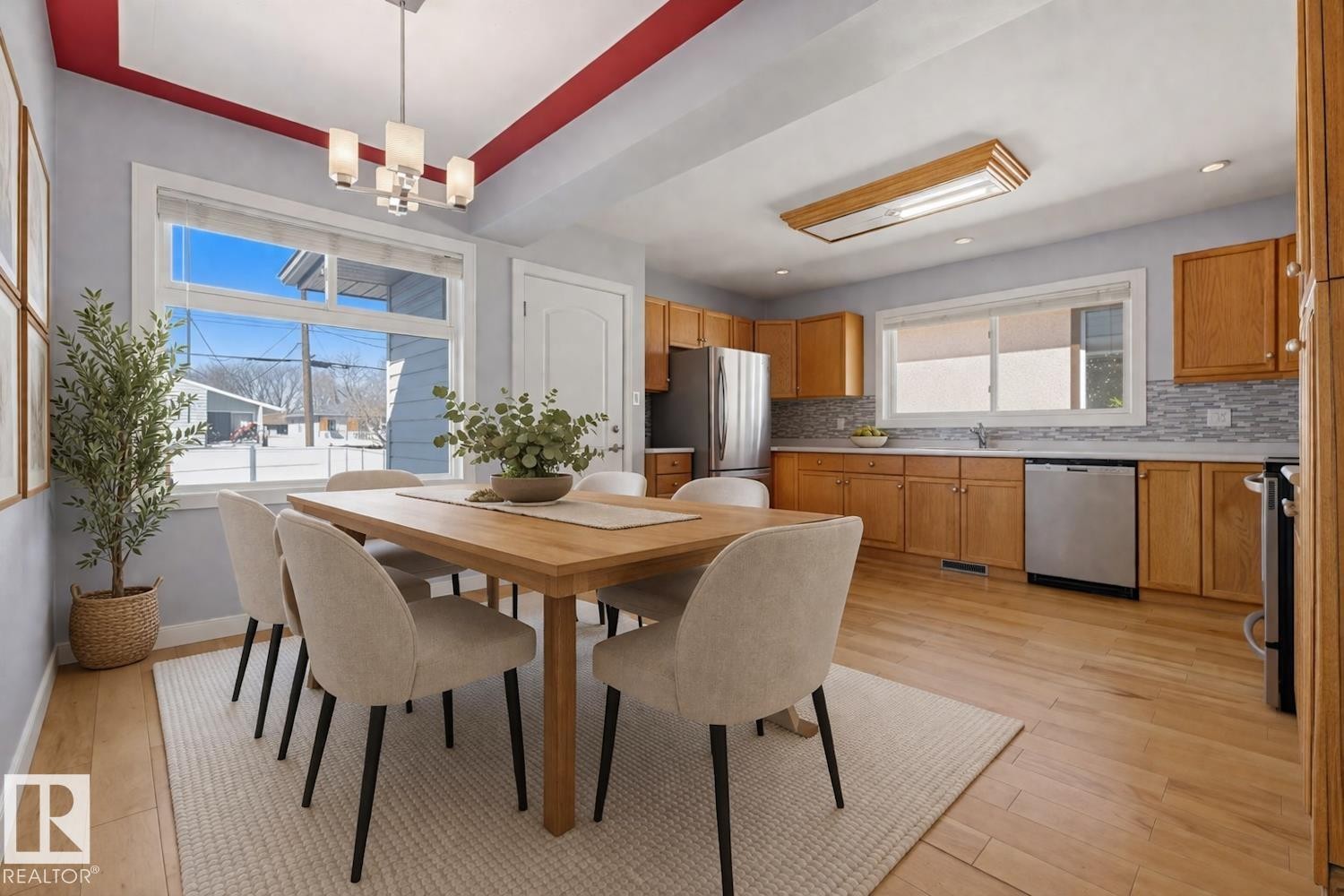 This open-concept dining area features hardwood floors, a large window providing natural light, and a modern chandelier - 10612 79 Street, Edmonton, AB