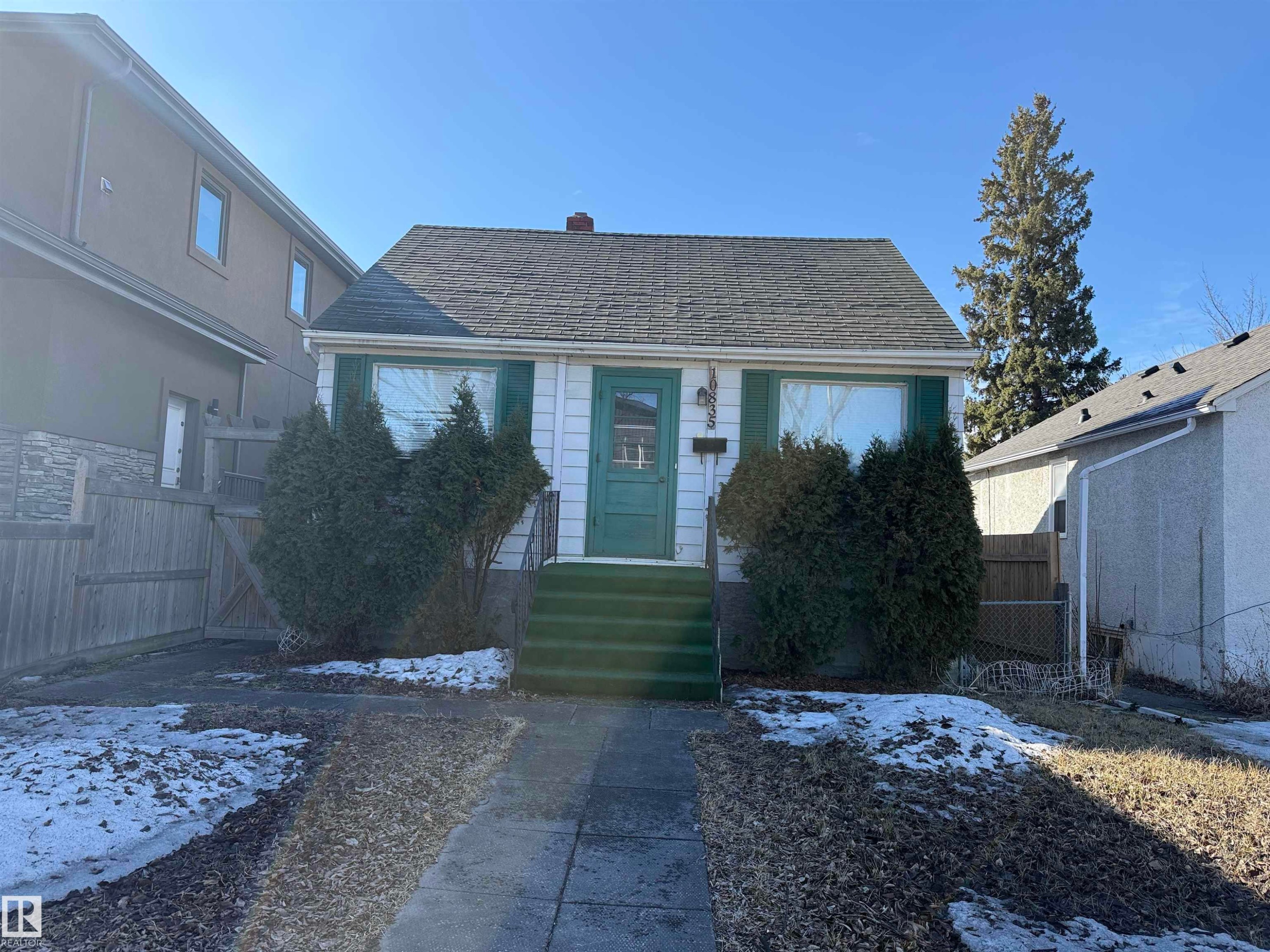 The property features a traditional exterior with white siding, green window shutters, and a green front door - 10835 73 Avenue, Edmonton, AB - Outdoor