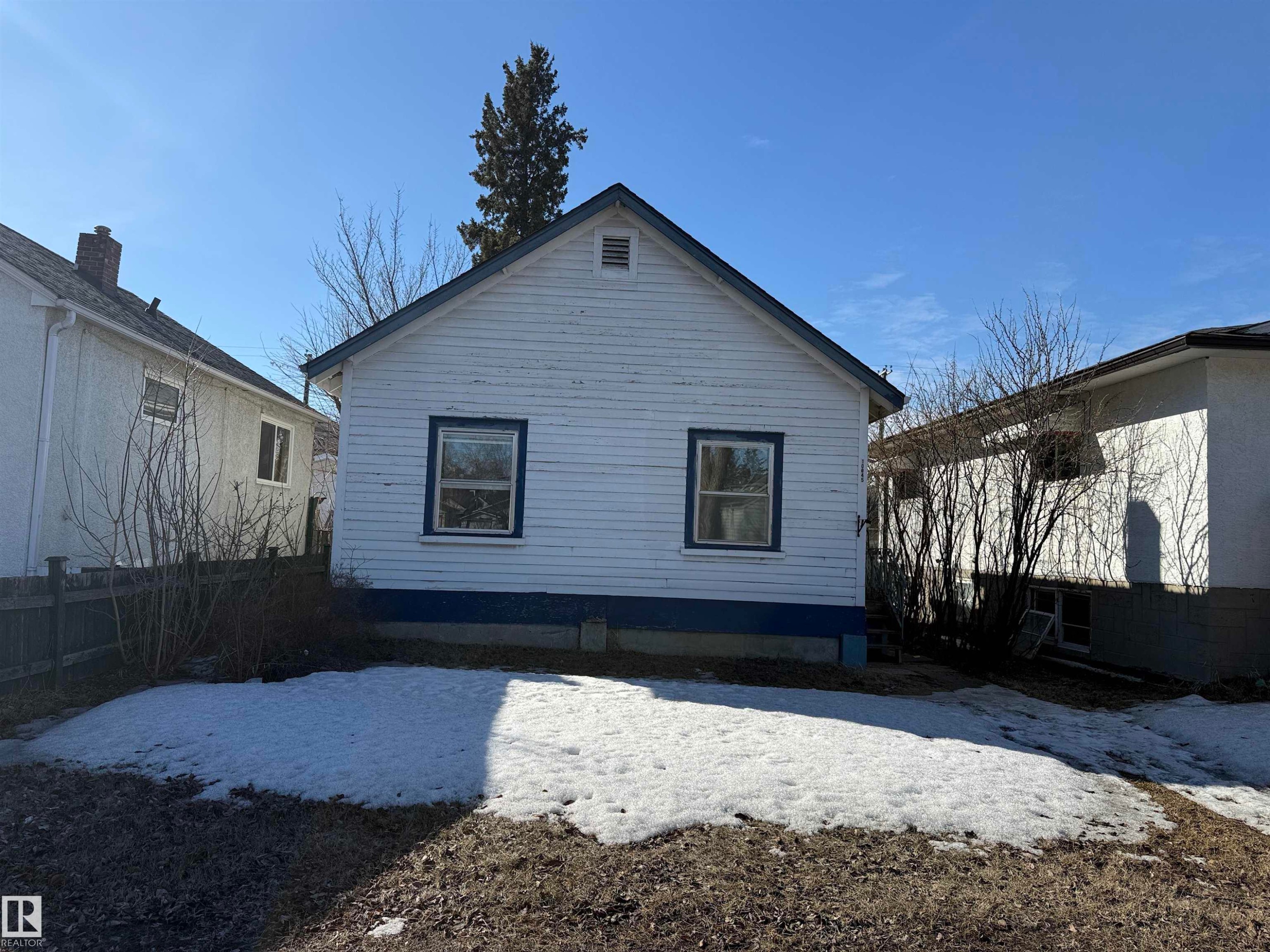 The property features a white exterior with blue trim accents and two windows on the visible side - 10845 73 Avenue Nw, Edmonton, AB
