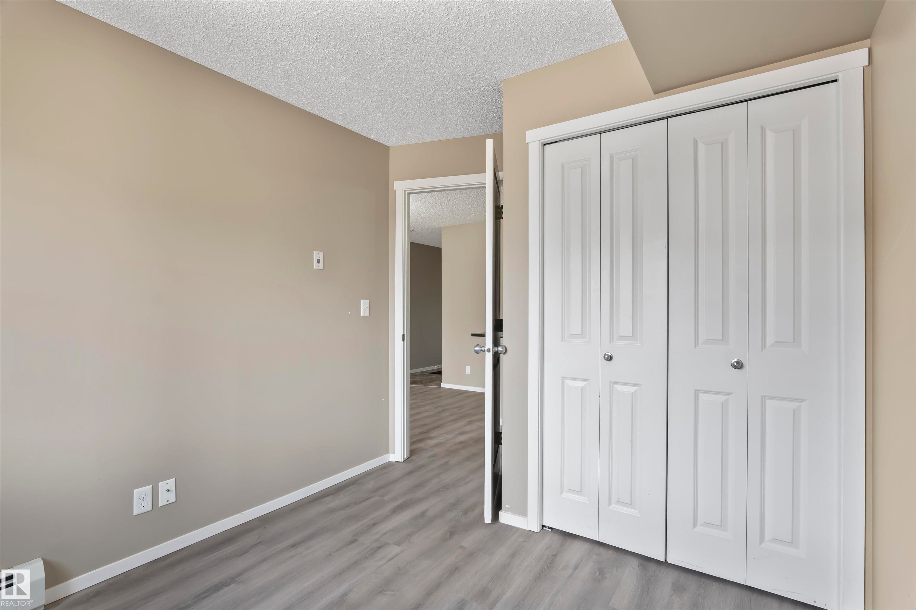 This room features grey flooring, neutral wall paint, and a white bi-fold closet - 214 5816 Mullen Place, Edmonton, AB - Indoor