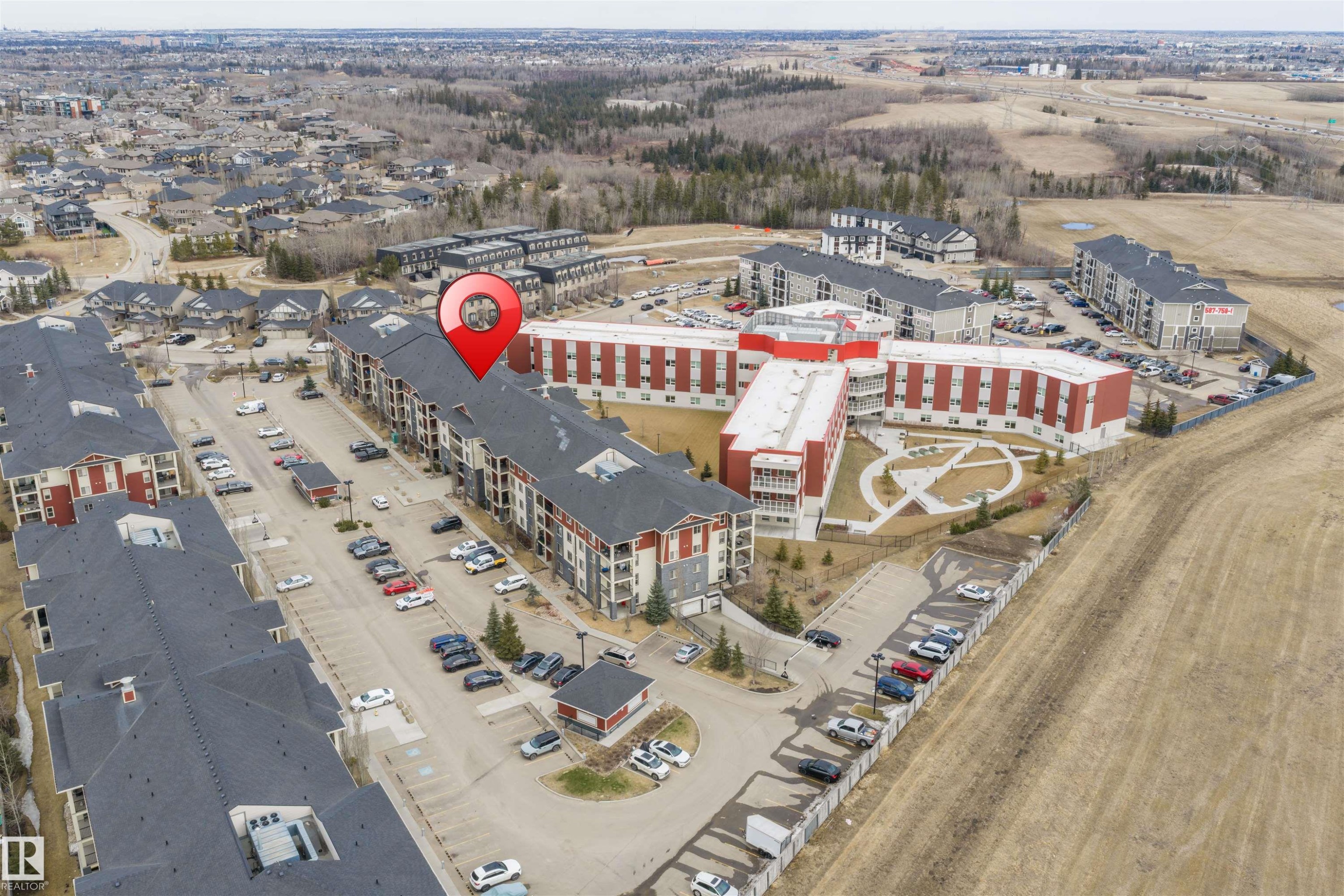 Aerial view of the property and surrounding area, showcasing the established neighborhood and nearby undeveloped land - 214 5816 Mullen Place, Edmonton, AB - With View