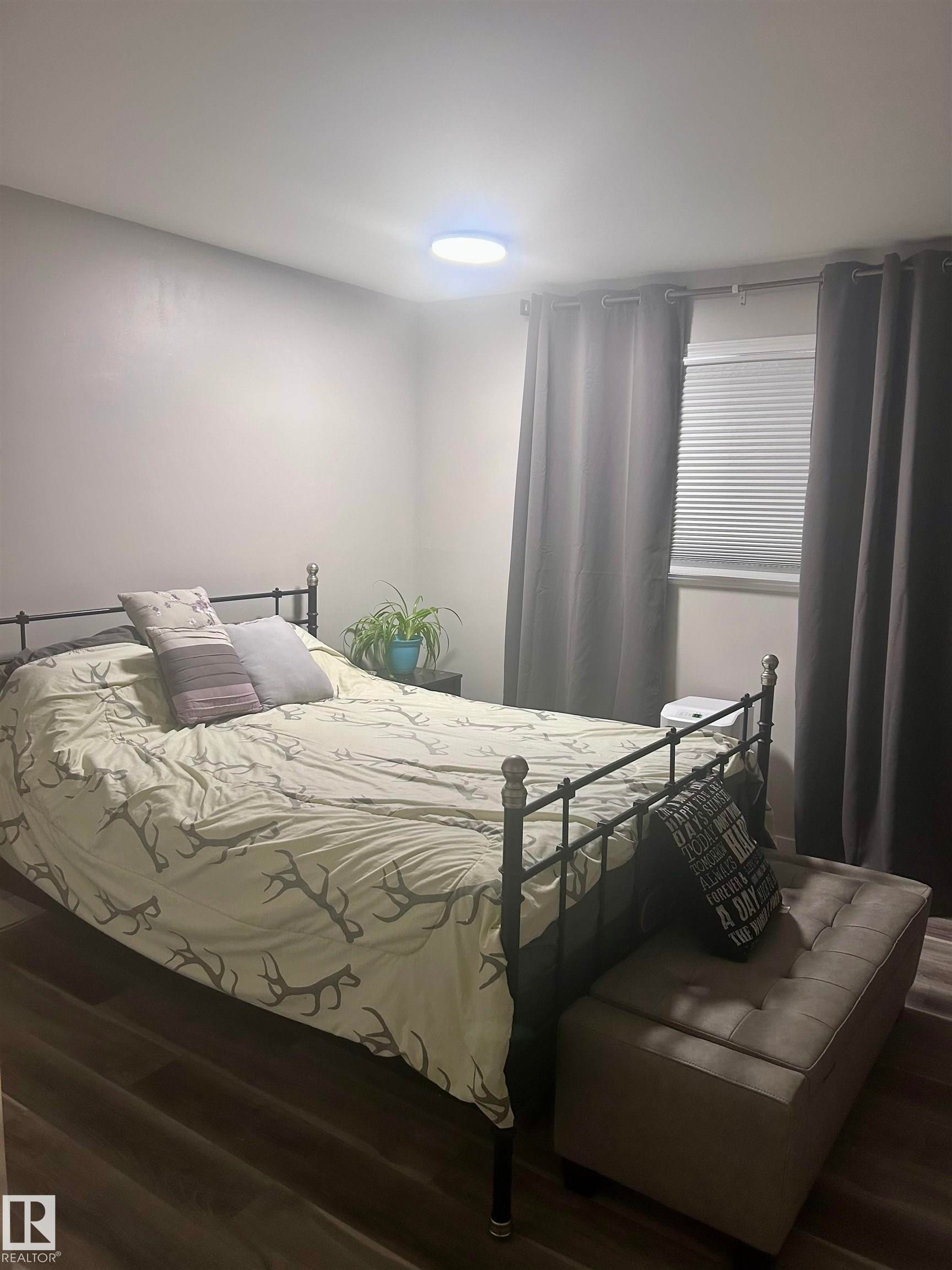 This room features durable plank flooring, a window with blinds, and a ceiling light fixture - 4515 54 Ave, Tofield, AB - Indoor Photo Showing Bedroom