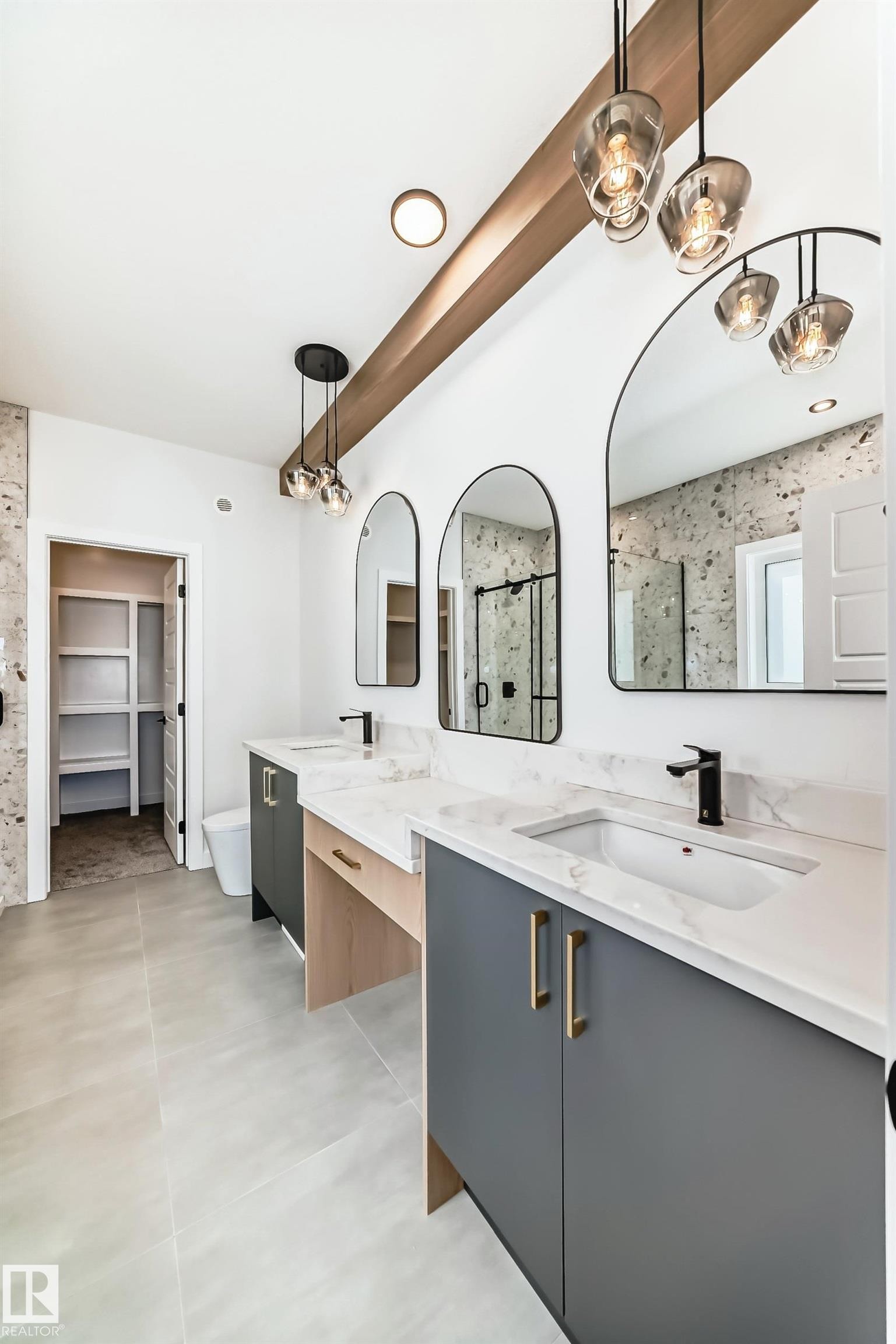 The bathroom features a double vanity with grey cabinetry, white countertops, and modern light fixtures, complemented by two arched mirrors - 341 Roberts Wynd, Leduc, AB - Indoor Photo Showing Kitchen