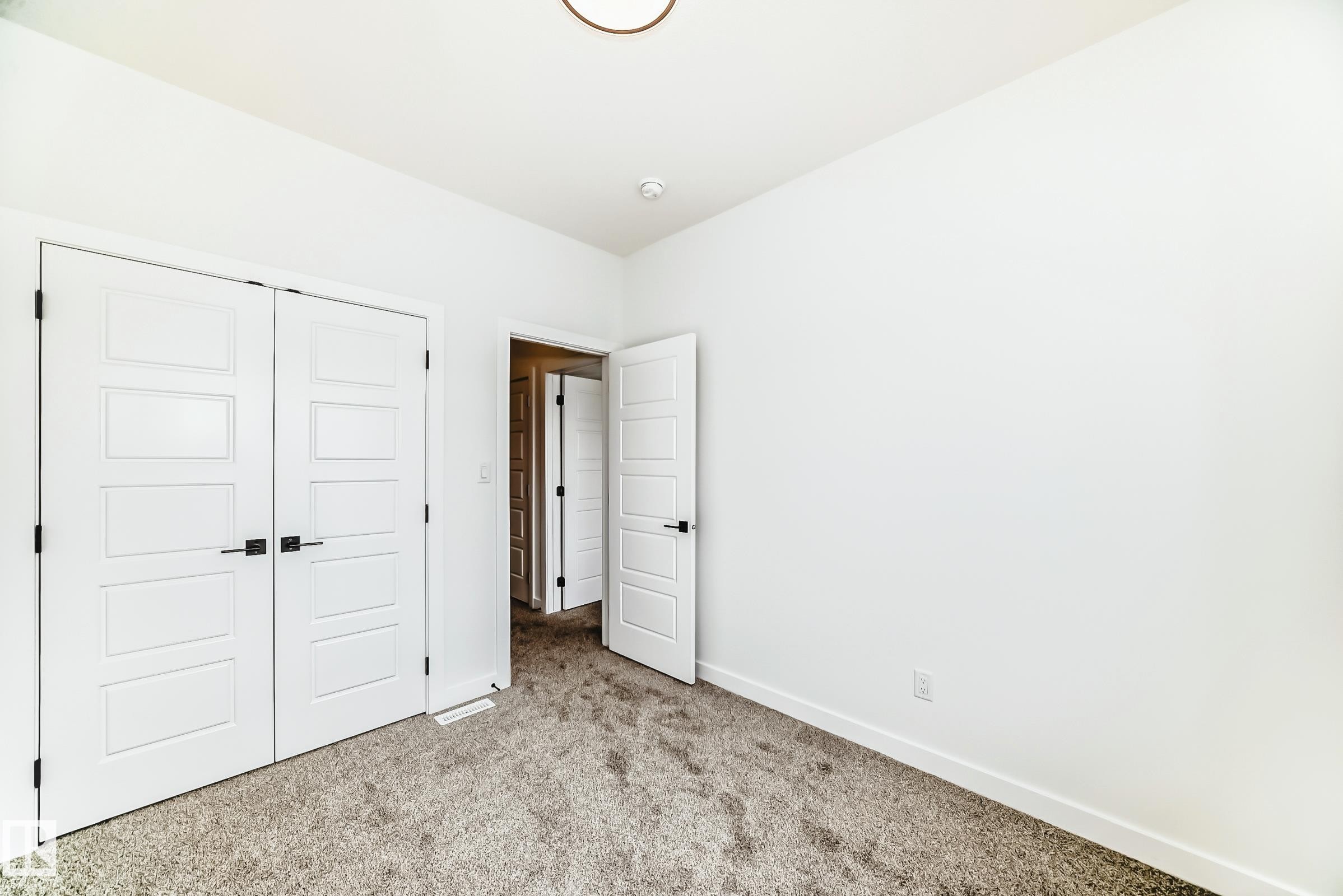 The property includes a room with light-colored carpet, white walls, and white doors with dark hardware - 341 Roberts Wynd, Leduc, AB - Indoor Photo Showing Other Room