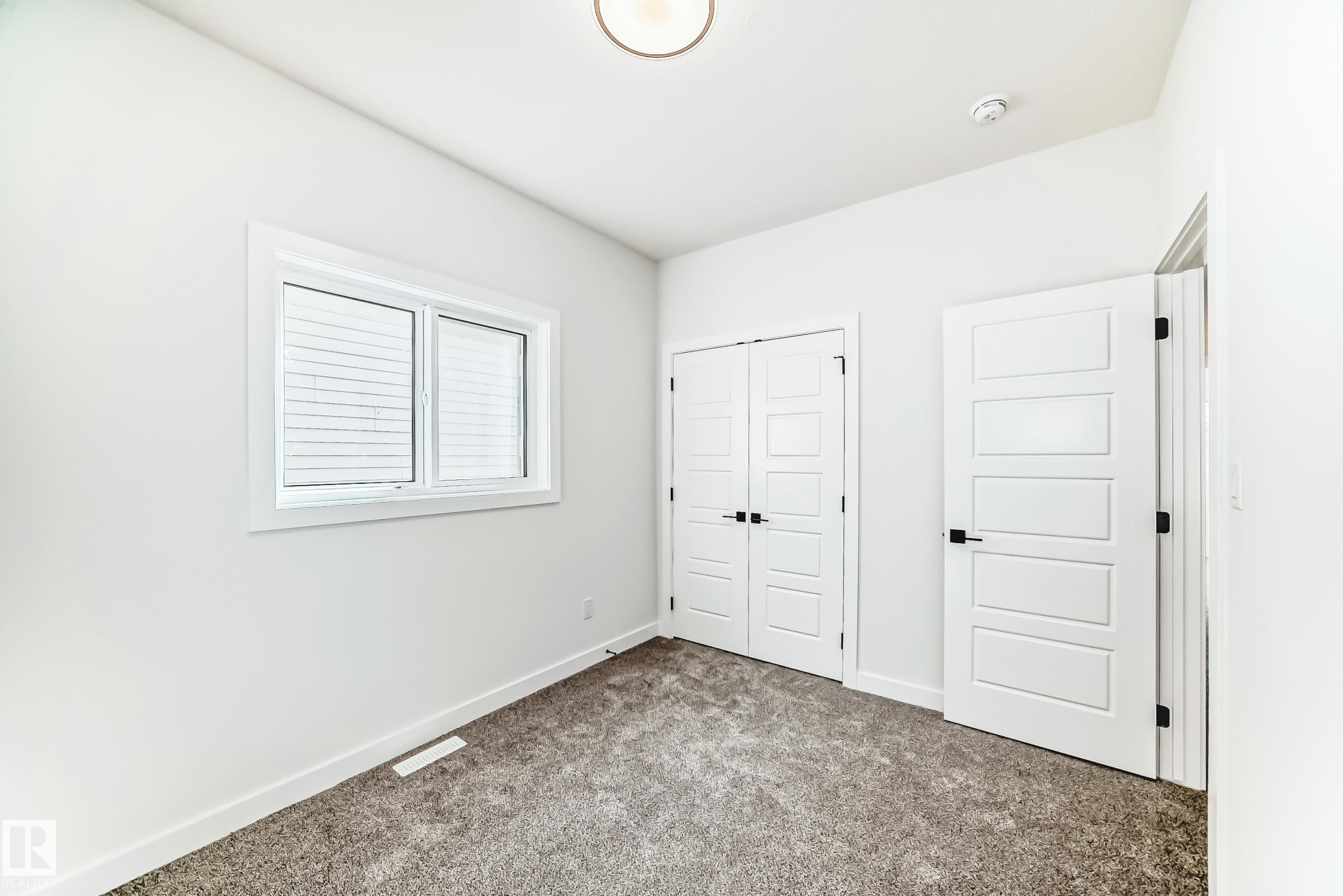 This bright interior space features white walls, clean white trim, and a window providing natural light - 341 Roberts Wynd, Leduc, AB - Indoor Photo Showing Other Room