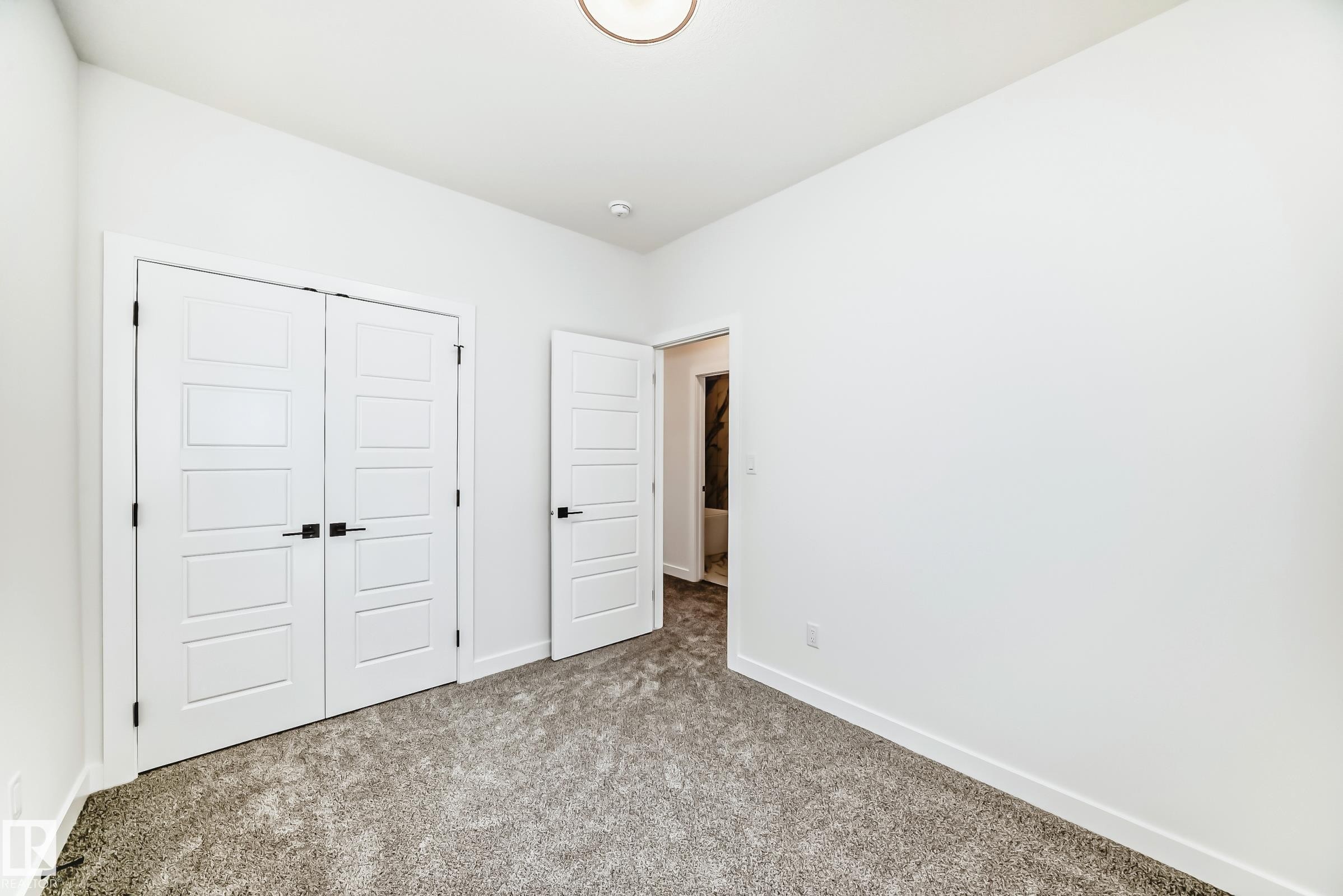 This room features white walls, gray carpeting, and white doors with black hardware - 341 Roberts Wynd, Leduc, AB - Indoor Photo Showing Other Room