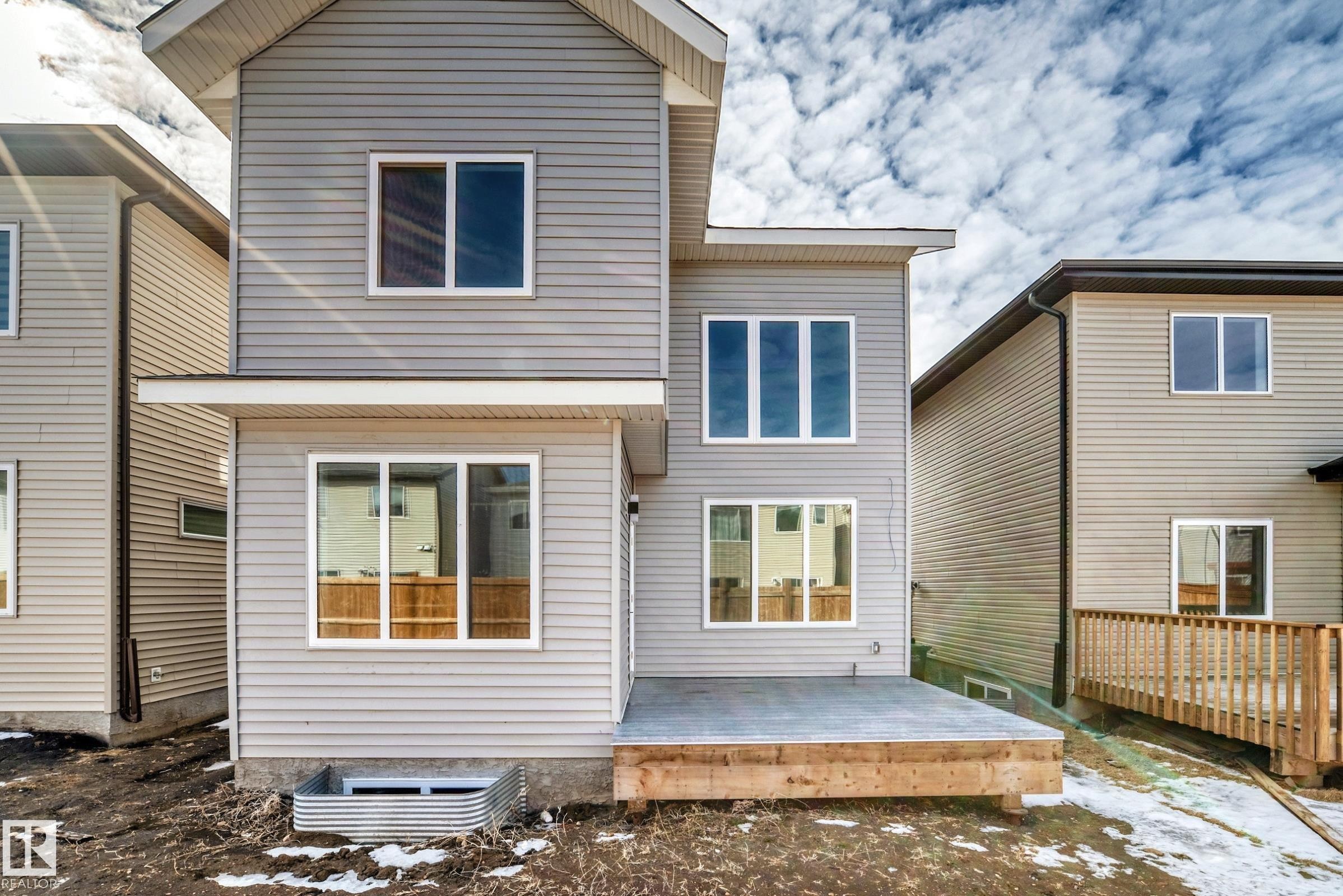 The property features light gray horizontal siding, white window frames, and a wooden deck - 341 Roberts Wynd, Leduc, AB - Outdoor With Deck Patio Veranda With Exterior