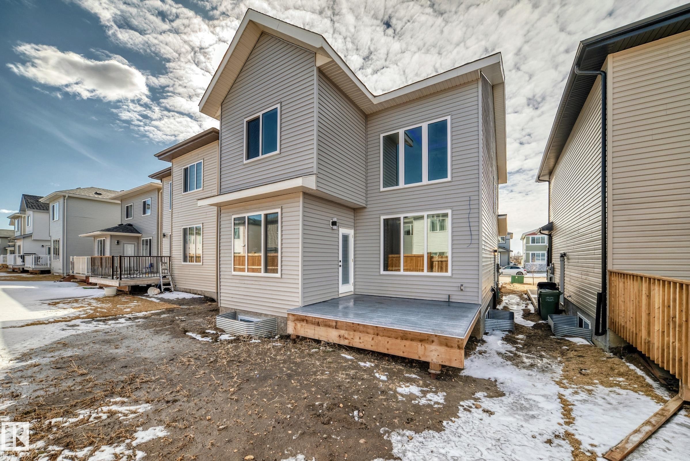 The property features light gray horizontal siding, an elevated rear deck, and numerous windows providing natural light - 341 Roberts Wynd, Leduc, AB - Outdoor With Exterior