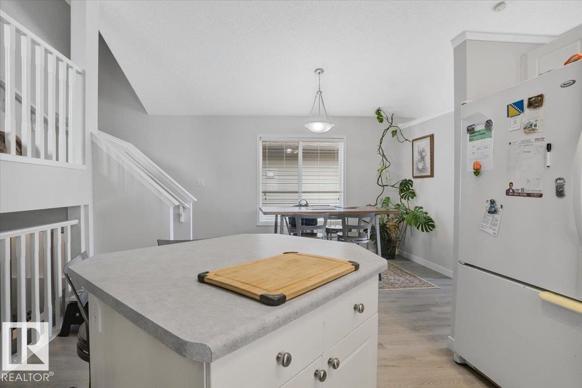 The kitchen features a white refrigerator and an island with a light-colored countertop - 3119 32 Avenue, Edmonton, AB - Indoor