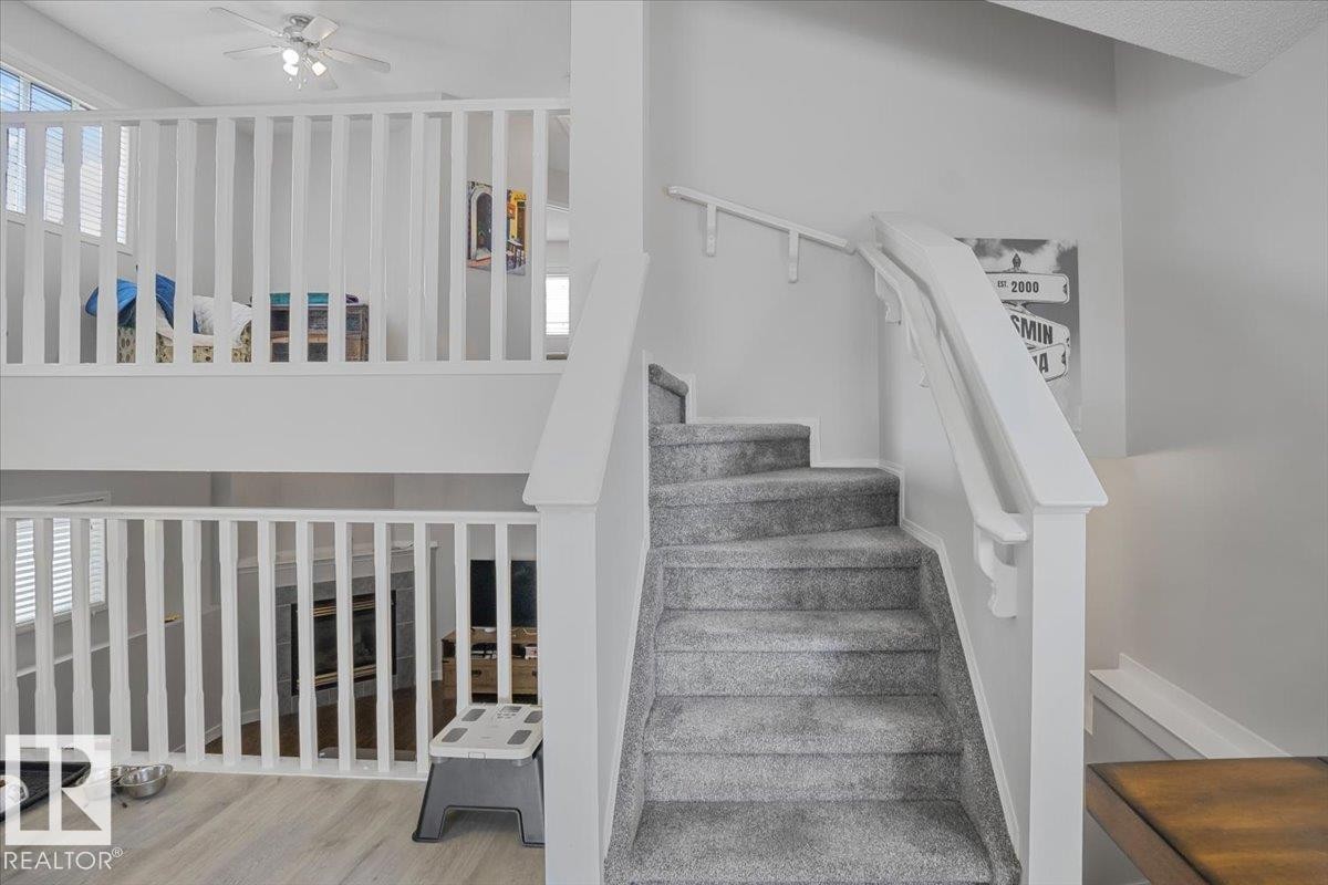 Carpeted staircase with white railings, featuring a view of the lower and upper levels of the property, each with white banisters and white walls - 3119 32 Avenue, Edmonton, AB - Indoor Photo Showing Other Room
