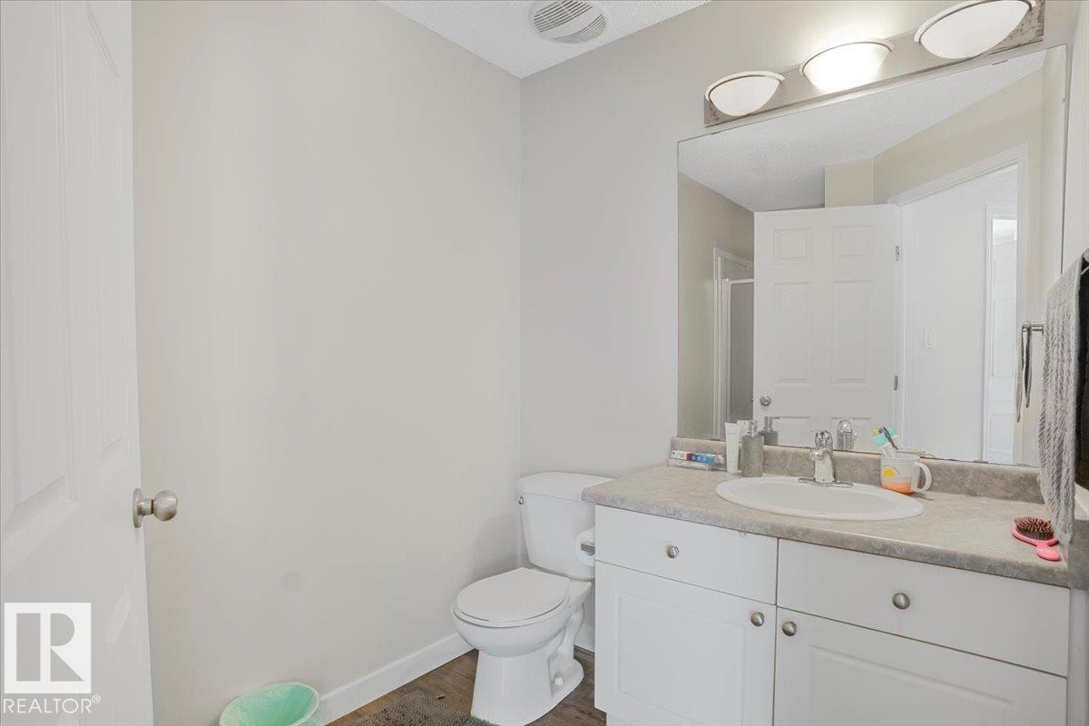 The bathroom features a white vanity with a single sink, a large mirror, and overhead lighting - 3119 32 Avenue, Edmonton, AB - Indoor Photo Showing Bathroom