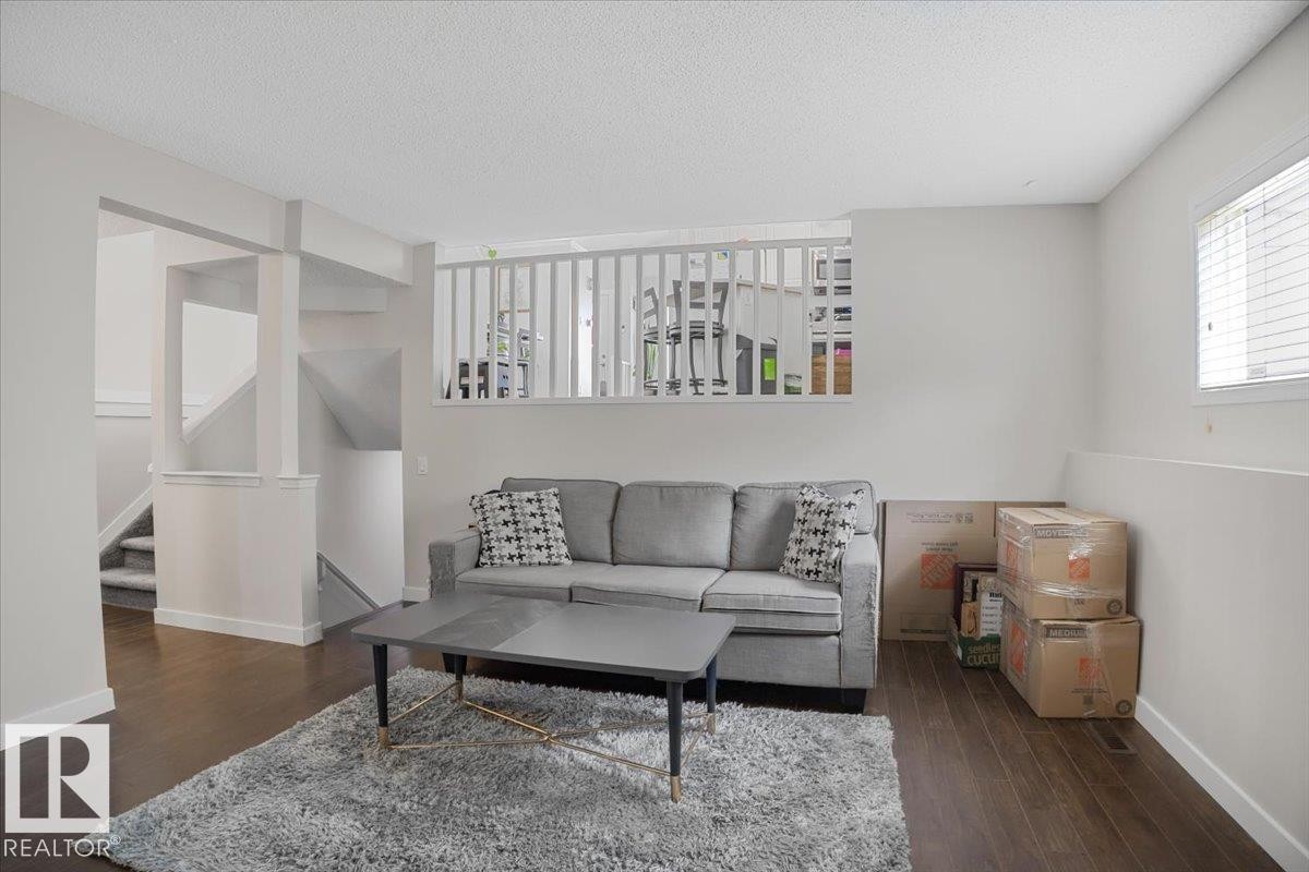 Living area featuring dark hardwood floors, light-colored walls, and a window with blinds - 3119 32 Avenue, Edmonton, AB - Indoor Photo Showing Living Room