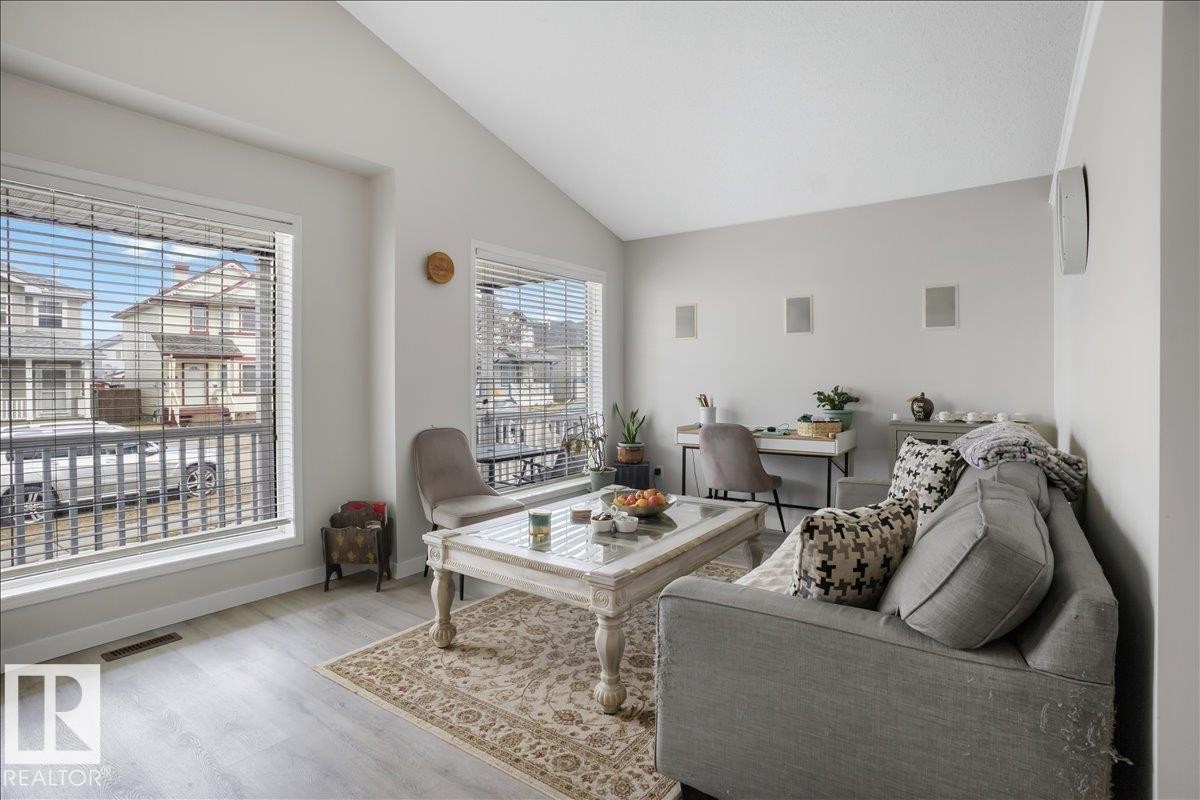 The living area features a vaulted ceiling, light-toned walls, and a large window with blinds providing natural light - 3119 32 Avenue, Edmonton, AB - Indoor Photo Showing Living Room