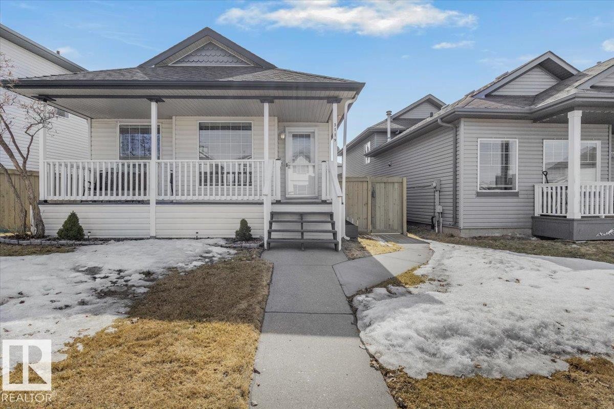 The property features a charming covered front porch with white railing, a grey shingle roof, and a paved walkway leading to the front entrance - 3119 32 Avenue, Edmonton, AB - Outdoor With Deck Patio Veranda With Facade