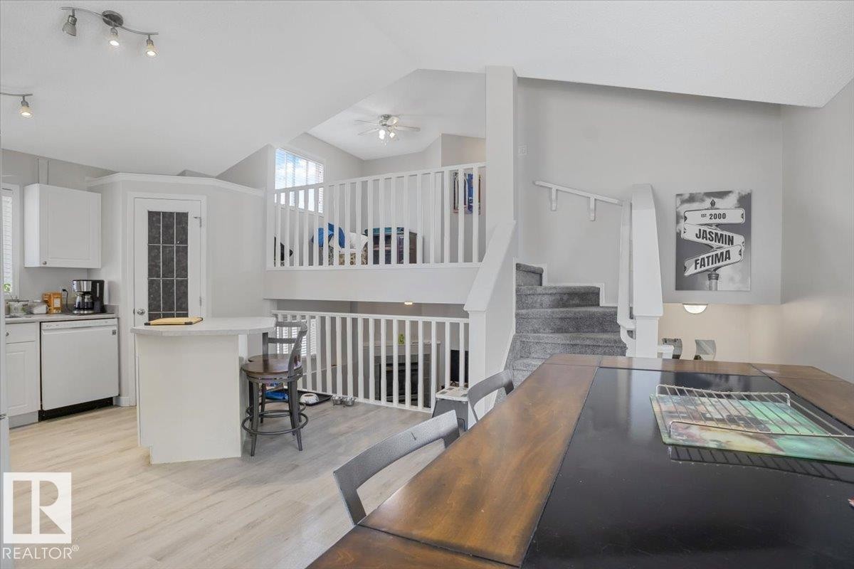 Open concept living area featuring light-colored flooring, a kitchen area with white cabinetry, and a dining area with a dark wood table - 3119 32 Avenue, Edmonton, AB - Indoor Photo Showing Other Room