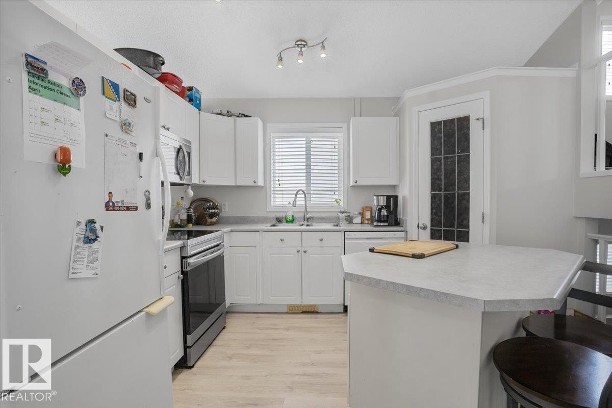 The kitchen features white cabinetry, light-colored countertops, and light wood tone flooring - 3119 32 Avenue, Edmonton, AB - Indoor Photo Showing Kitchen