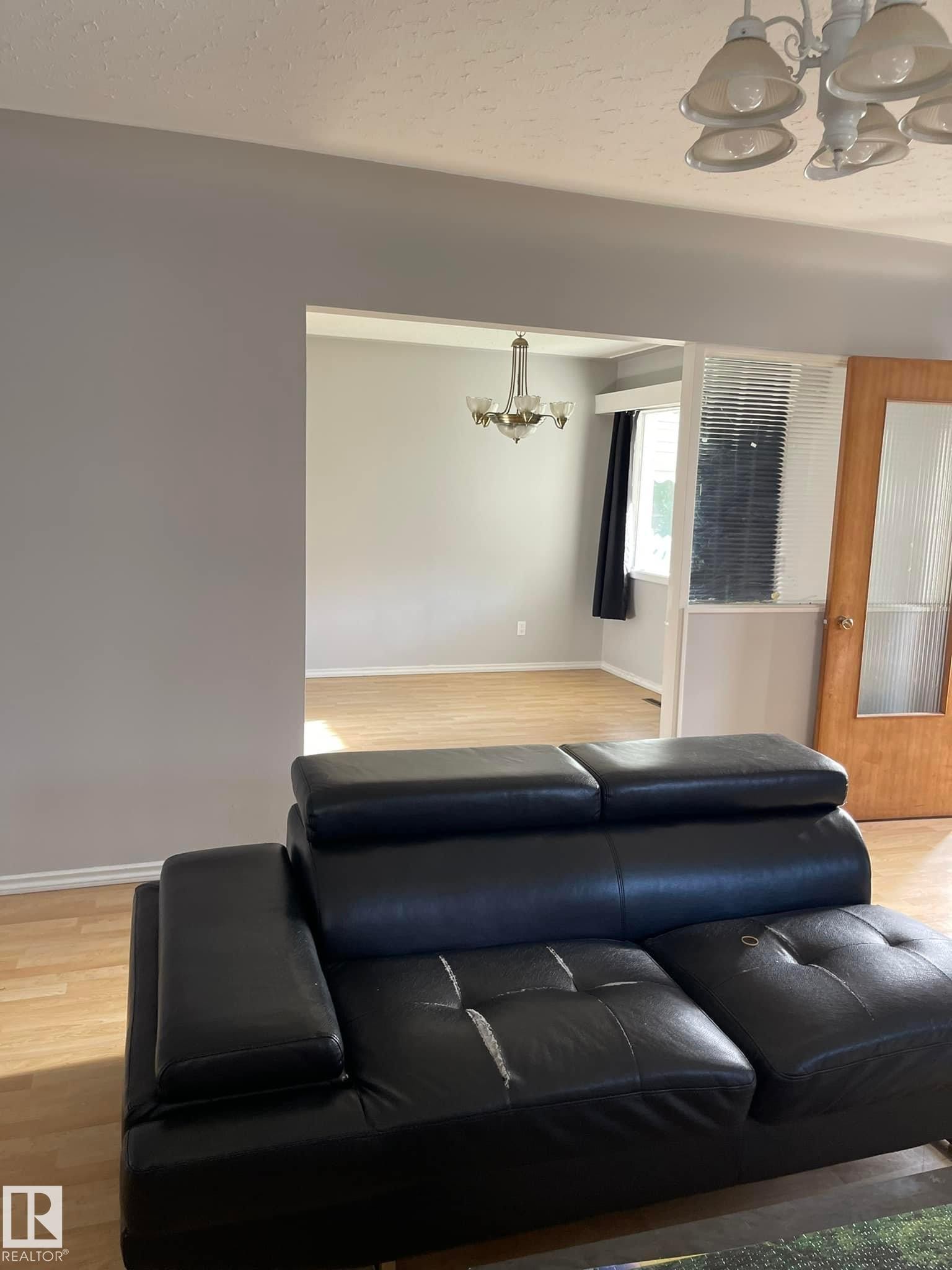 The property features an open floor plan with light-colored flooring and a chandelier in the dining area - 10965 96 Street Nw, Edmonton, AB - Indoor