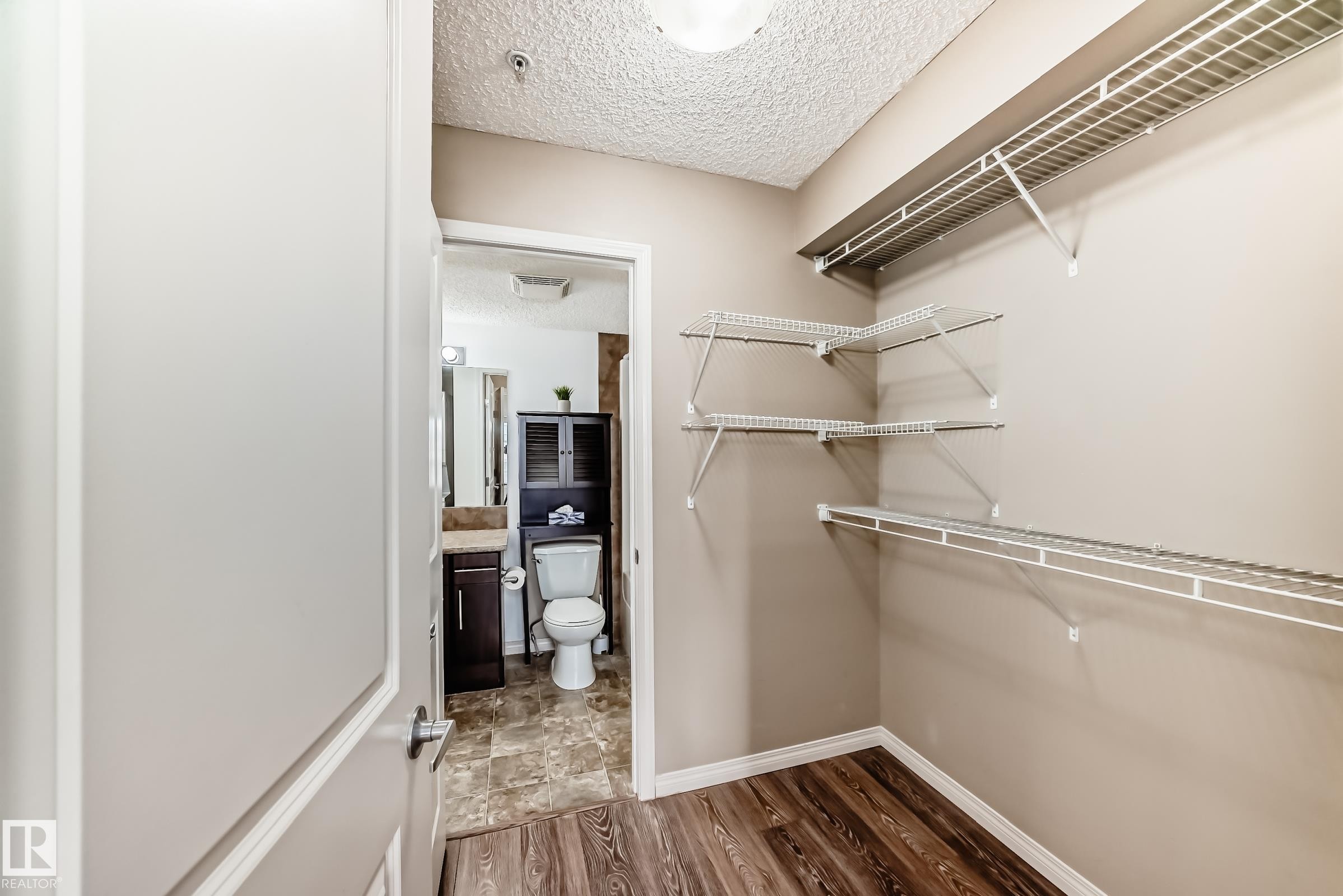 The property offers a walk-in closet with wire shelving, wood-style flooring, and a neutral wall color - 301 103 Ambleside Drive, Edmonton, AB - Indoor With Storage
